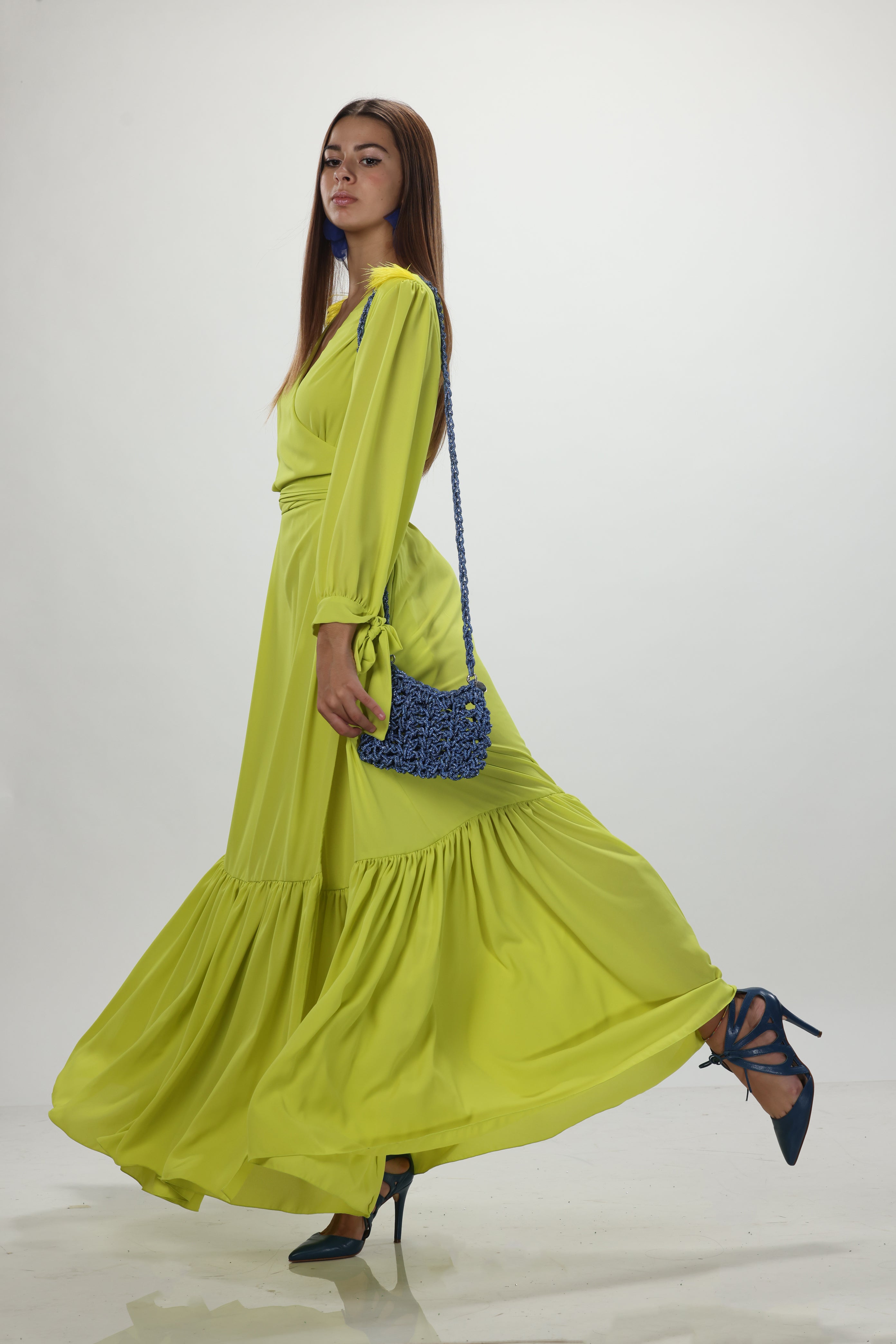 Blue handmade bag crafted with sparkling luminous thread, soft three-dimensional shape, braided handle and metal ring details worn by a female model.