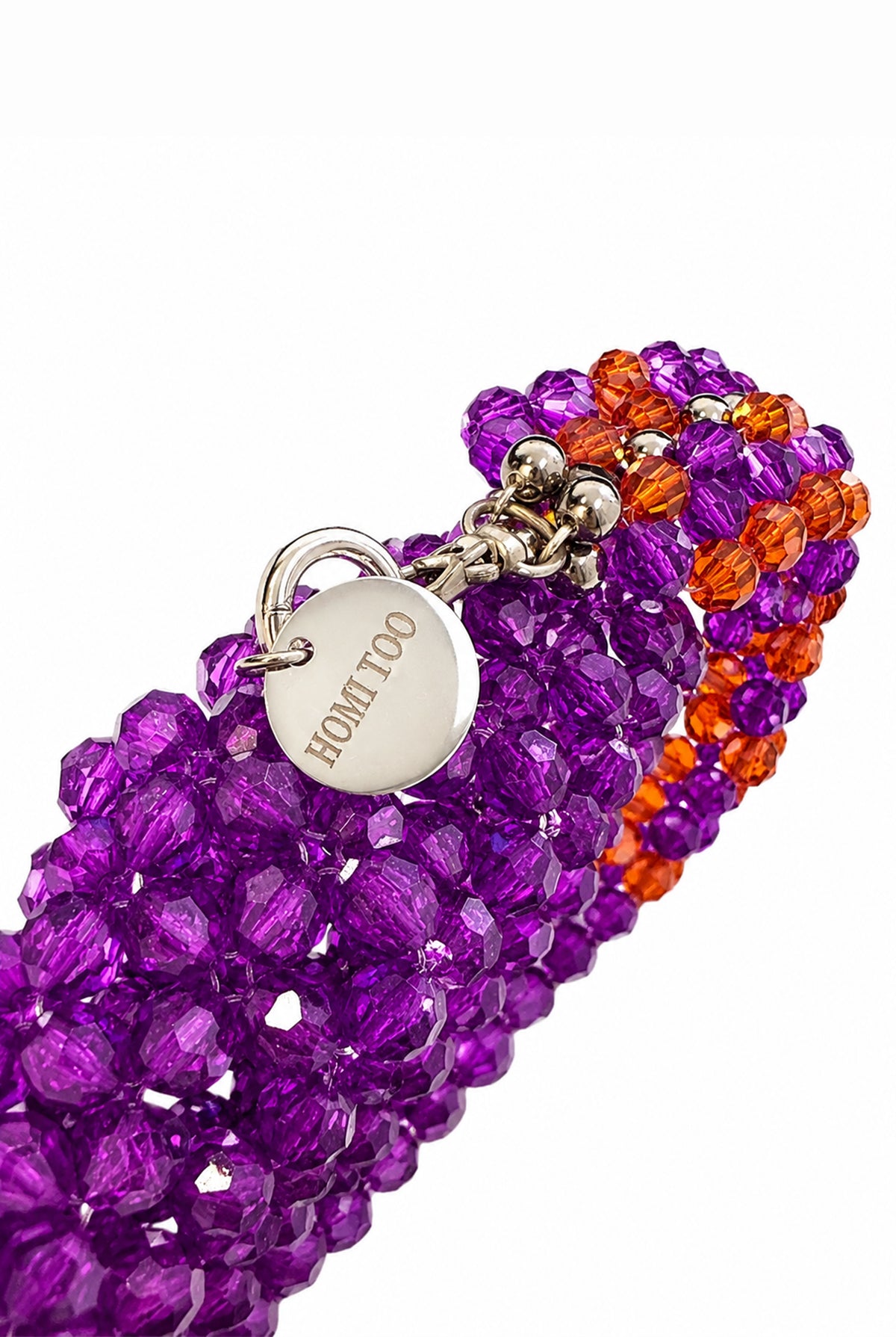 Detail of the HOMI TOO logo on the purple beaded bag.