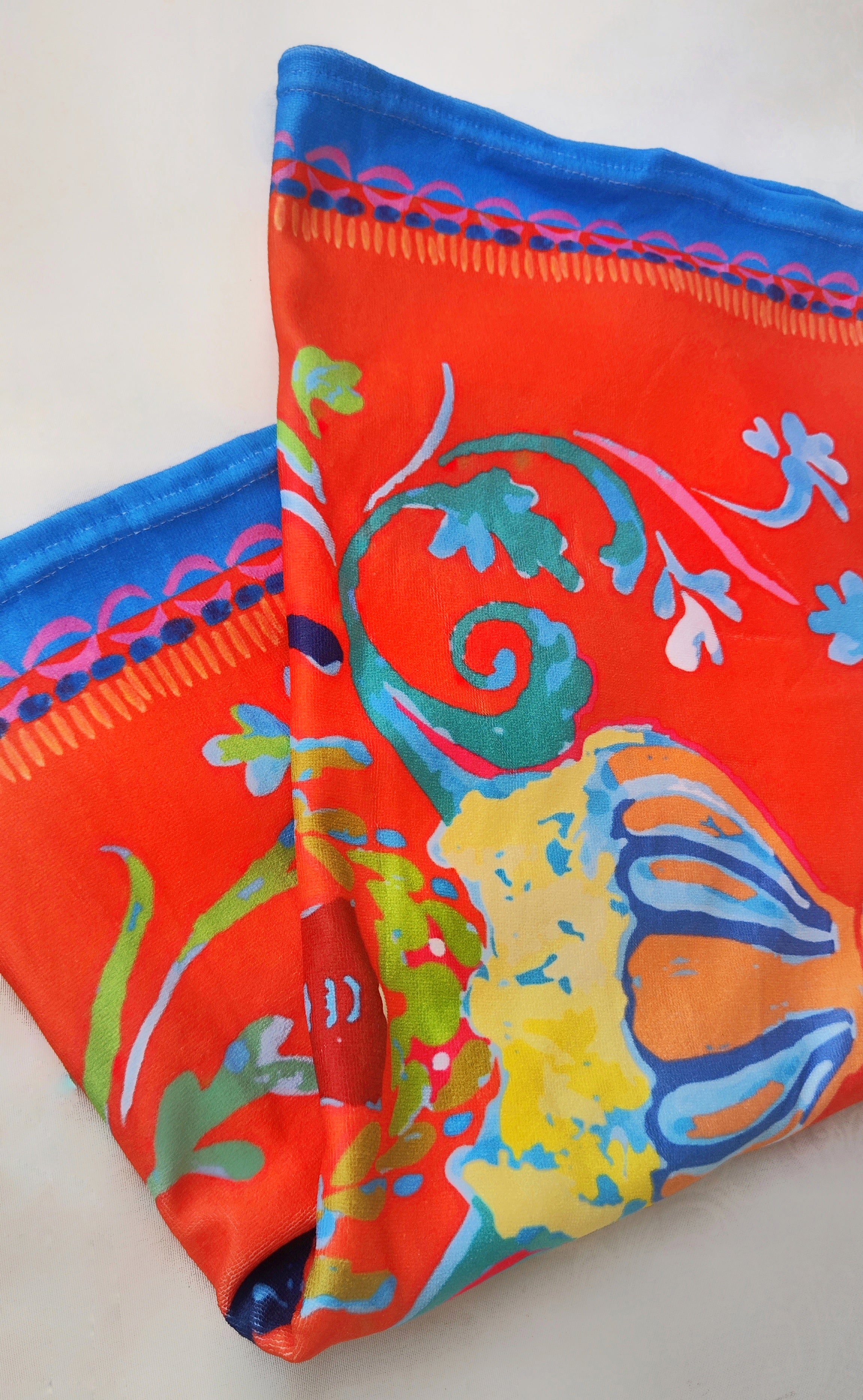 Close-up of the Sicilian-inspired print on the soft terry beach towel, highlighting red-orange colors and intricate patterns.