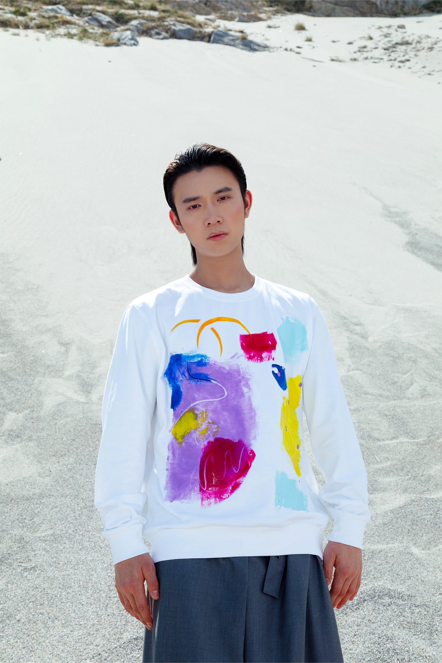 White oversized unisex sweatshirt worn by a model, featuring a colorful abstract relief silicone print on the front, made by hand, with soft and tactile texture.
