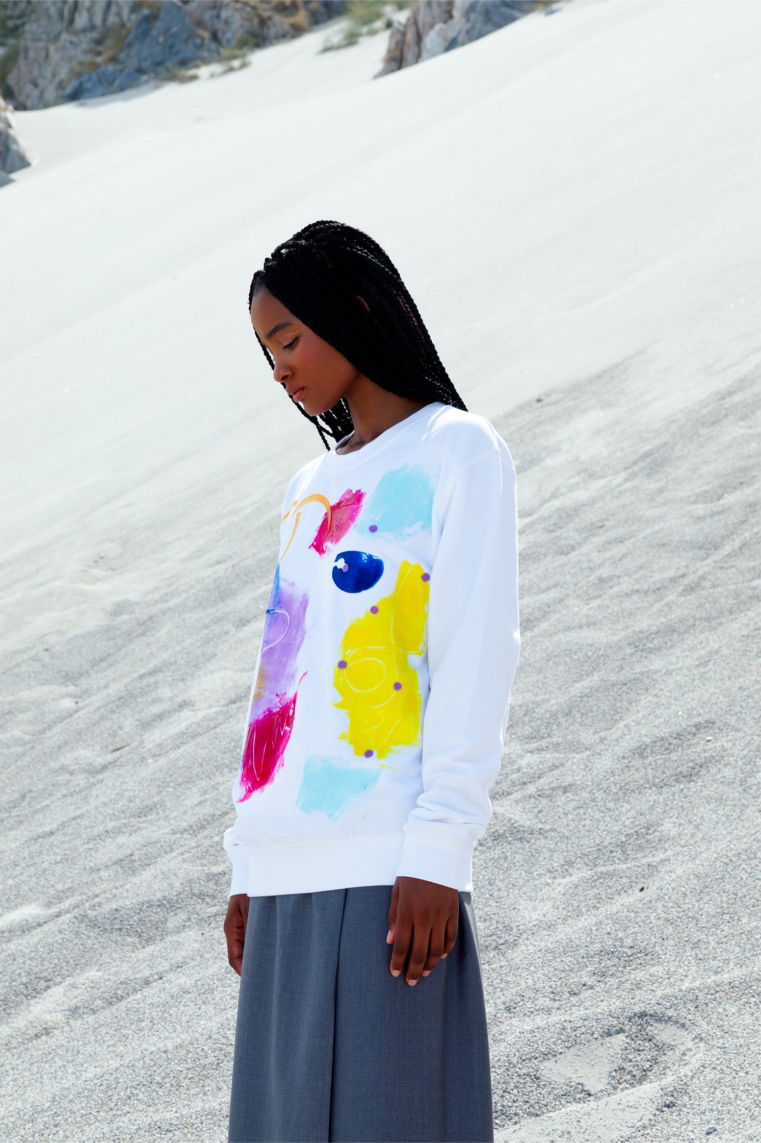 Side view of the white oversized unisex sweatshirt worn by a model, featuring a colorful abstract relief silicone print on the front, made by hand, with soft and tactile texture.