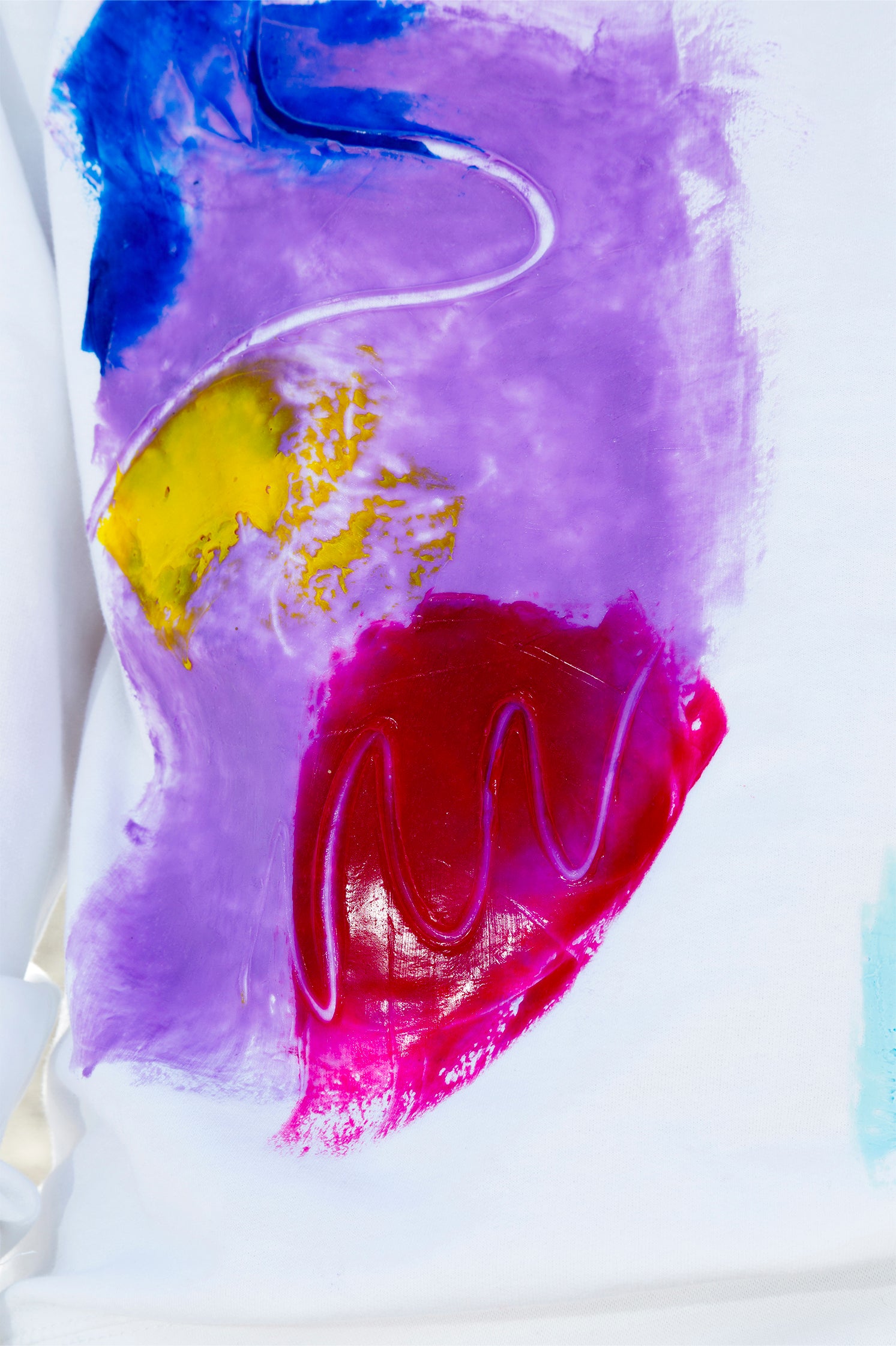 Close-up of the colorful abstract relief silicone print on the front of the white oversized sweatshirt, showing vibrant colors, tactile texture, and handmade craftsmanship.