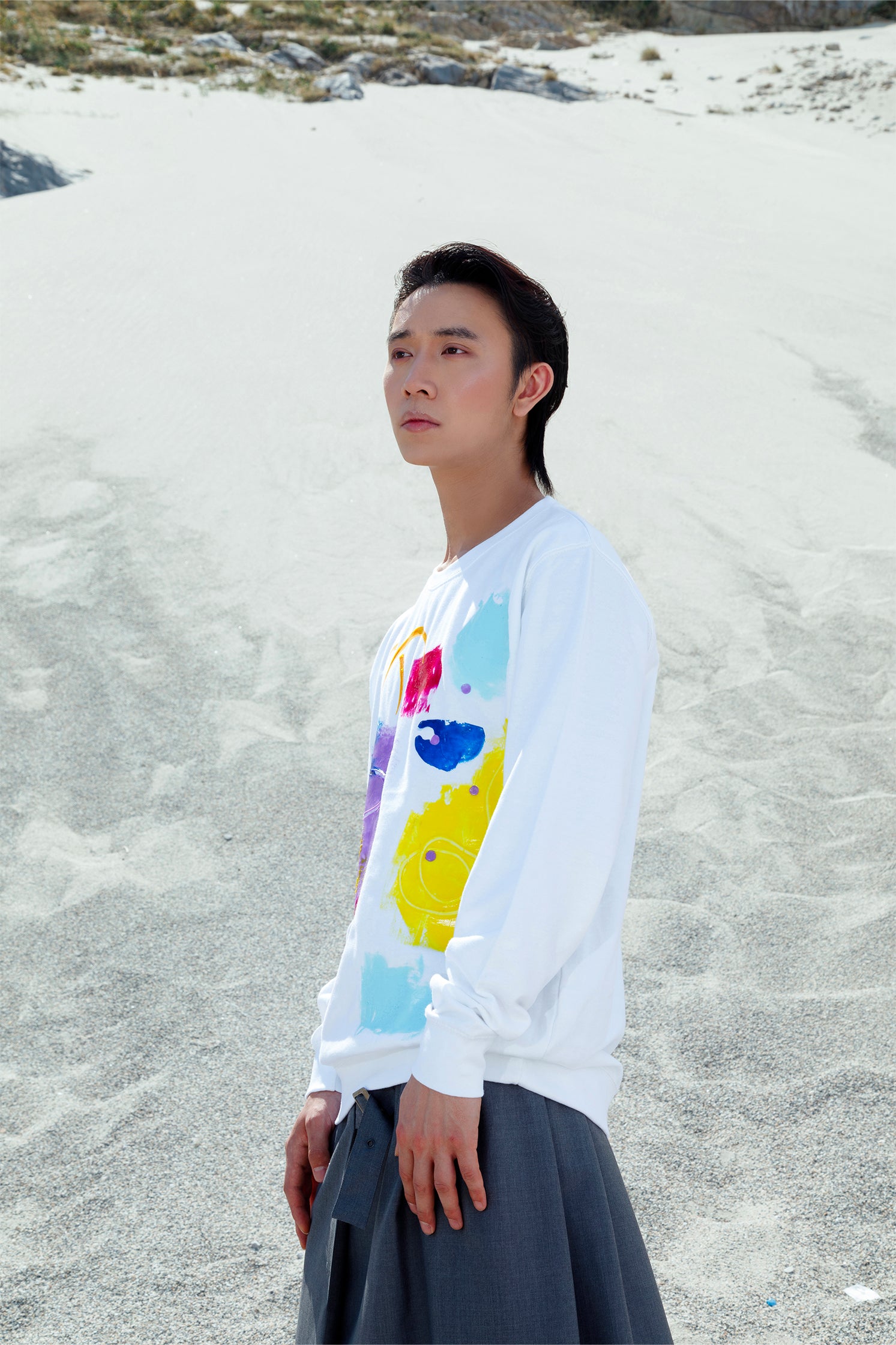 Side view of the white oversized unisex sweatshirt worn by a model, featuring a colorful abstract relief silicone print on the front, made by hand, with soft and tactile texture.