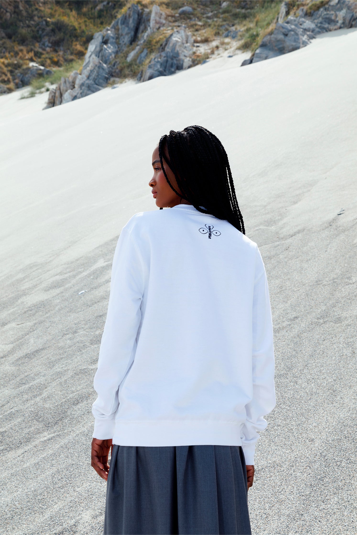 Back view of white oversized unisex sweatshirt worn by a model, showing the black scarab logo printed just below the collar.