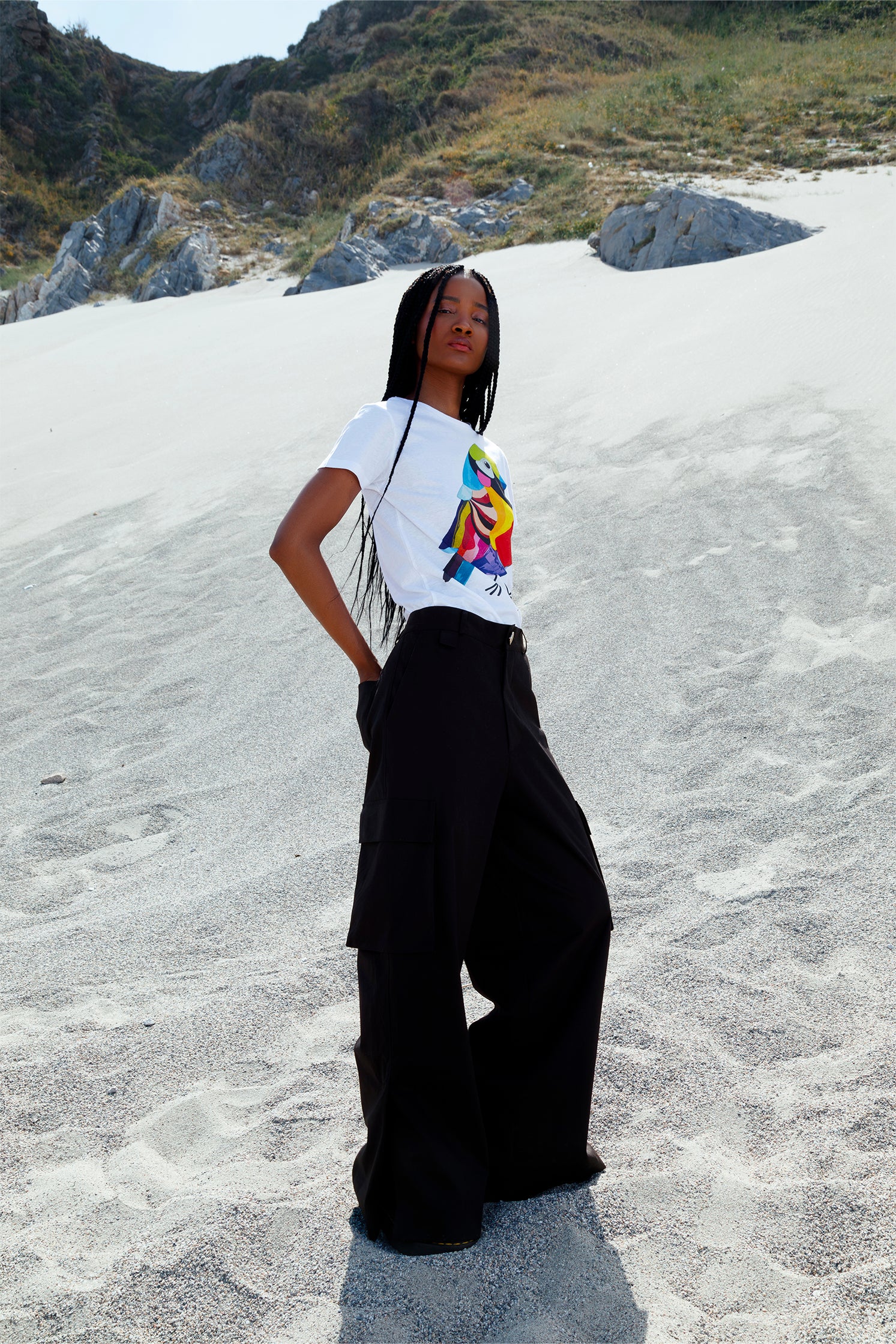 Unisex black cotton cargo pants worn by a model, featuring side patch pockets, relaxed fit, and small slit at the hem for added style and comfort.