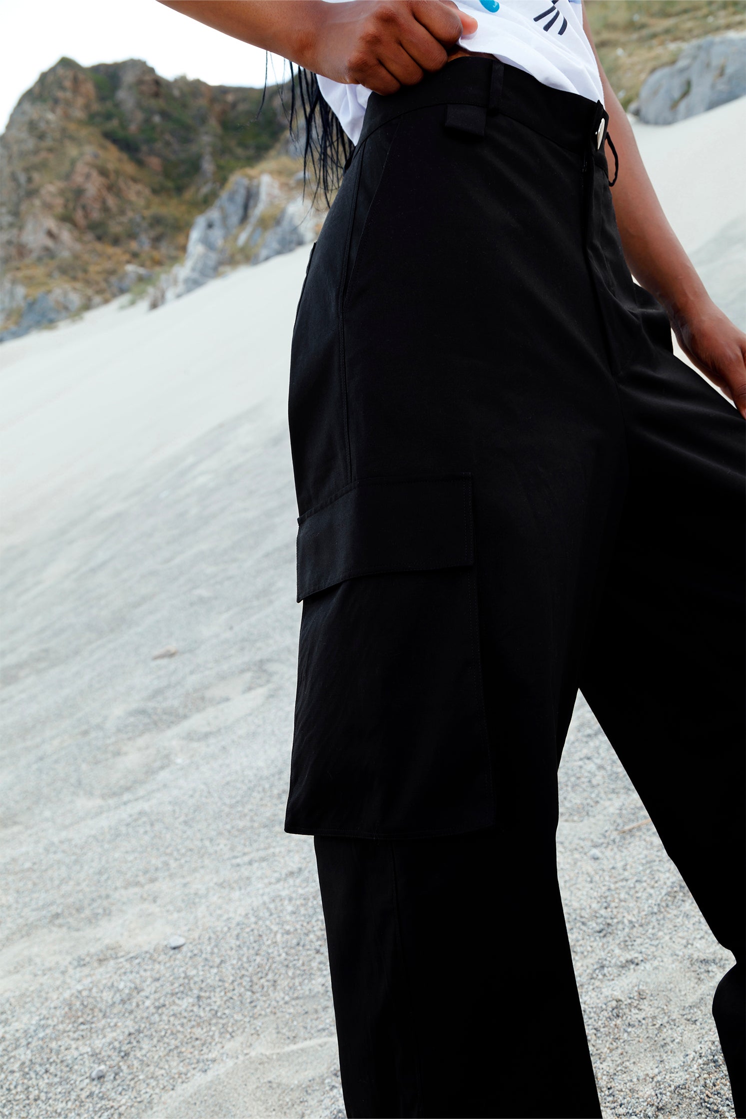 Close-up of the side patch pockets on the black cotton cargo pants, highlighting practical design and spacious storage.