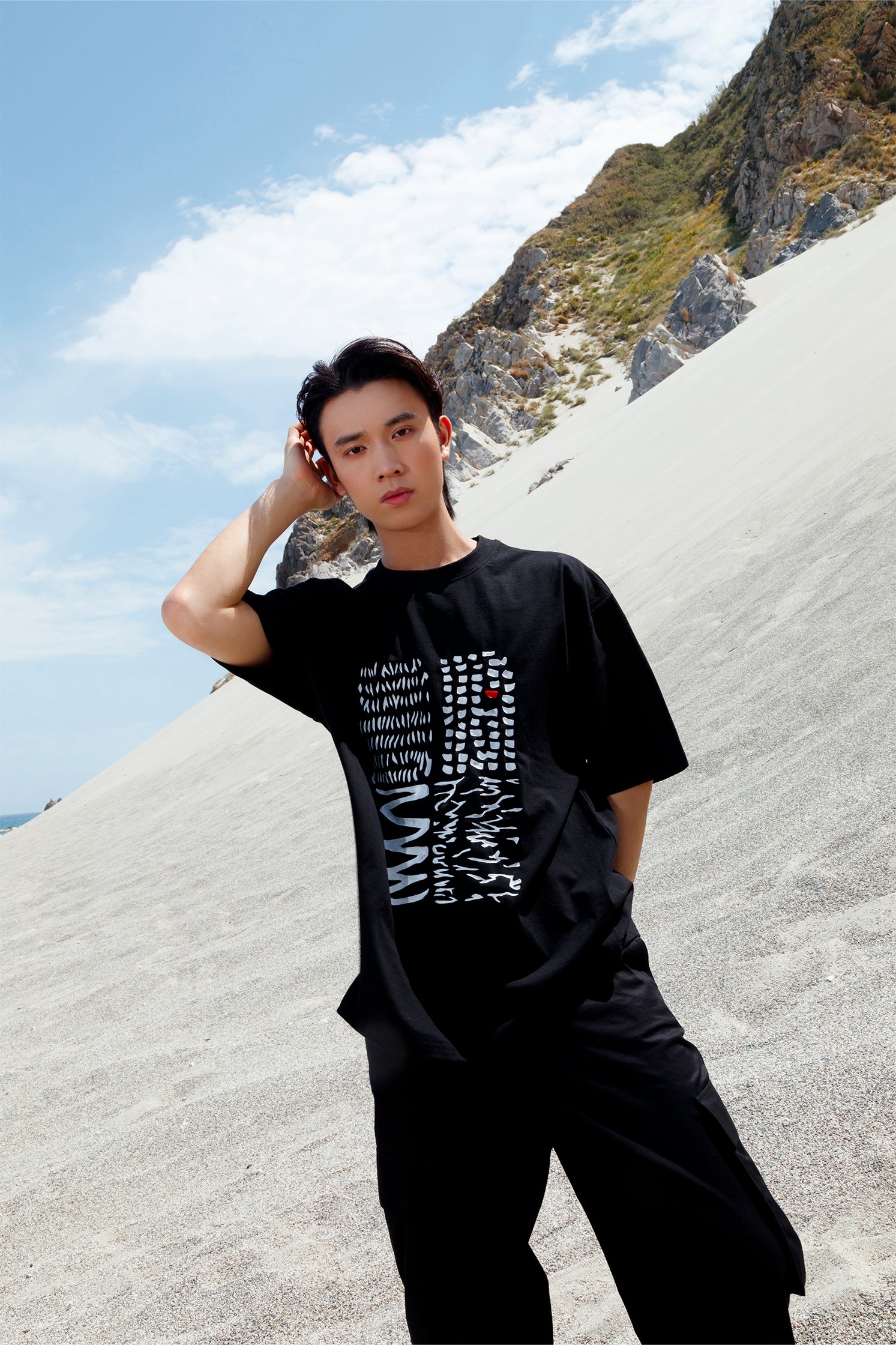 Black oversized unisex short-sleeved t-shirt worn by a model, featuring a hand-crafted abstract print on the front with white lines and a red detail in raised silicone.