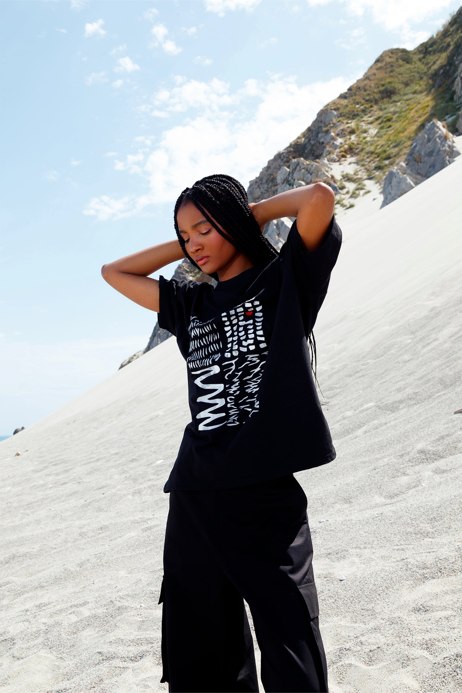 Black oversized unisex short-sleeved t-shirt worn by a model, featuring a hand-crafted abstract print on the front with white lines and a red detail in raised silicone.