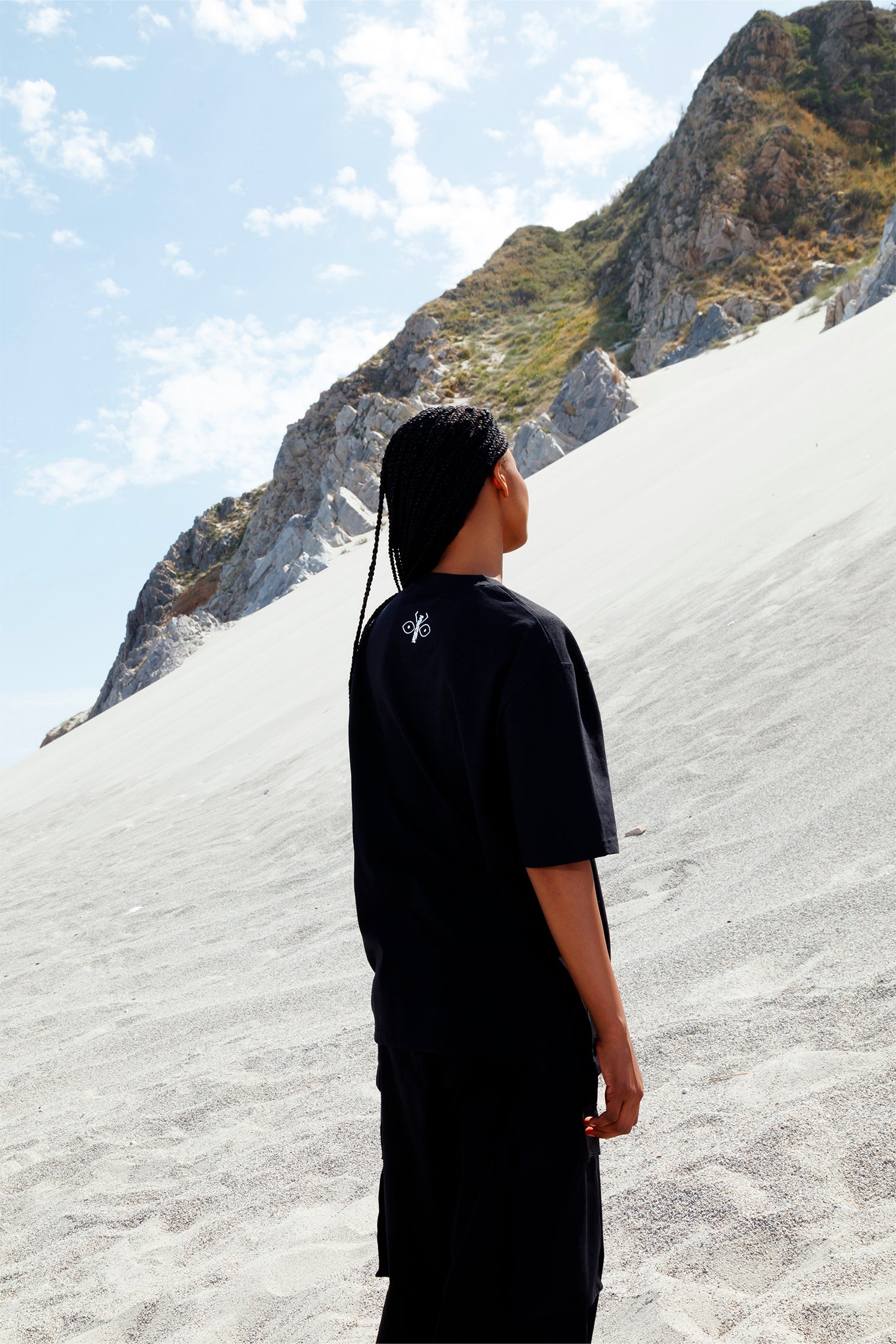 Back view of black oversized unisex t-shirt worn by a model, showing the white scarab logo printed just below the collar.