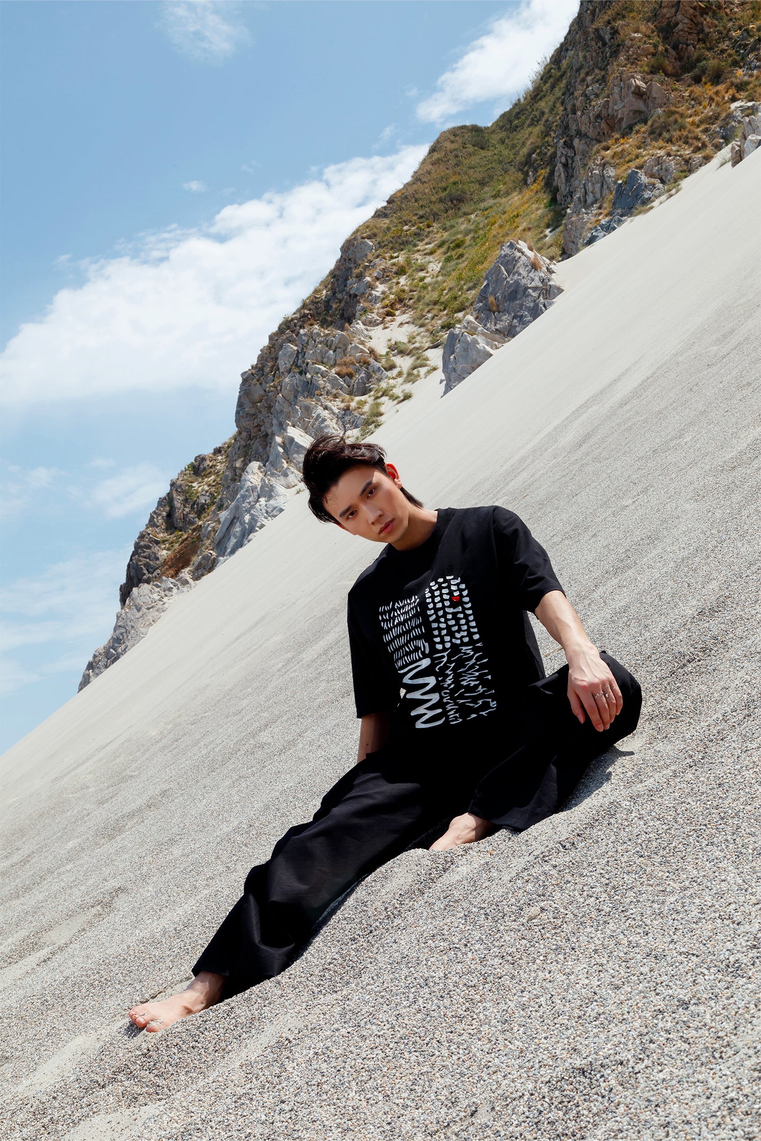 Black oversized unisex short-sleeved t-shirt worn by a model, featuring a hand-crafted abstract print on the front with white lines and a red detail in raised silicone.