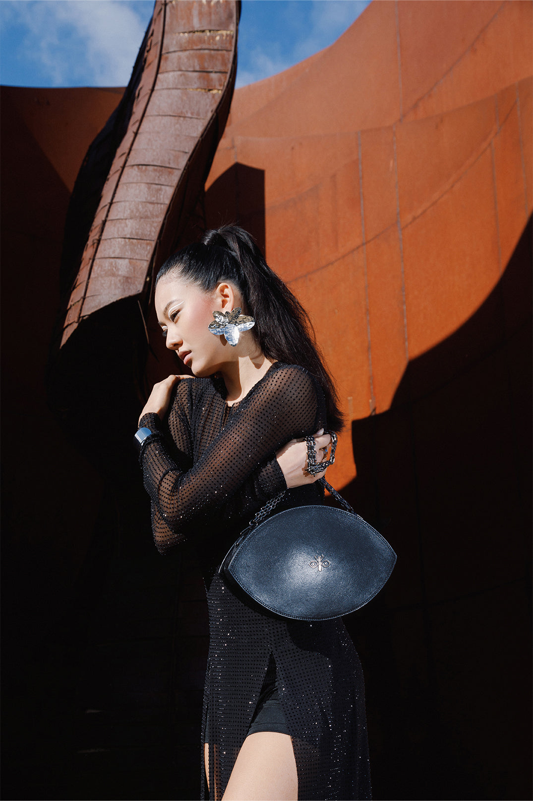Close-up of the lightweight black fabric of the dress worn by a model, adorned with sparkling micro rhinestones reflecting light for an elegant, sophisticated effect.