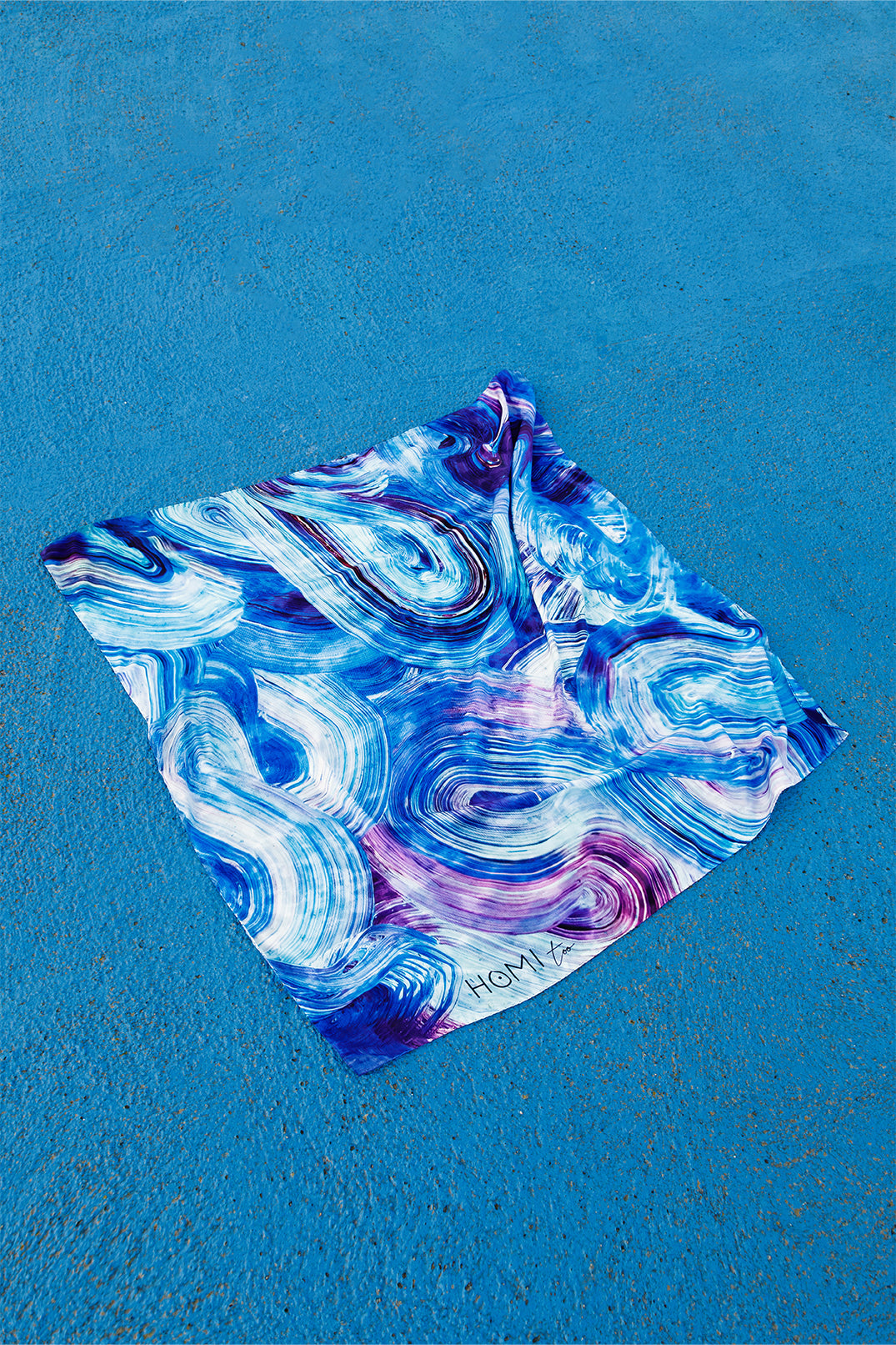 Silk twill scarf 90x90 cm with a print inspired by the movement of the sea, featuring fluid brushstrokes in different shades of blue that create an elegant and harmonious effect.