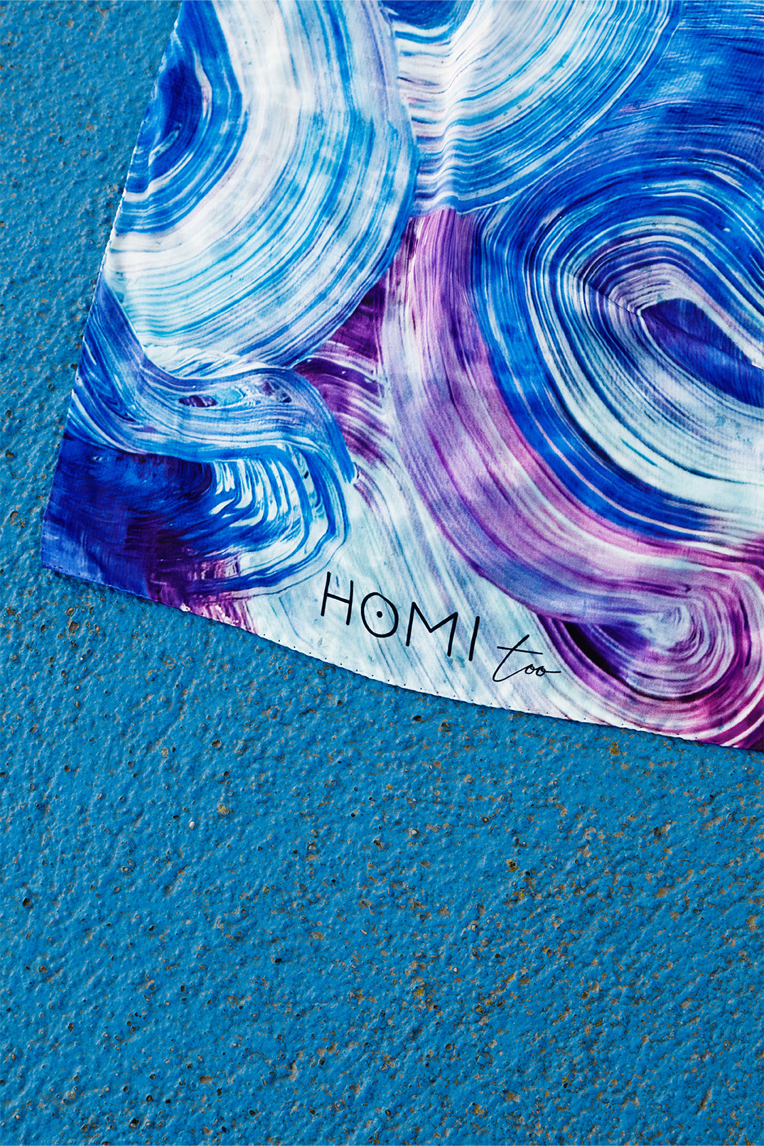 Close-up of the artistic print on the silk twill scarf, showing soft waves and brushstrokes in multiple shades of blue.