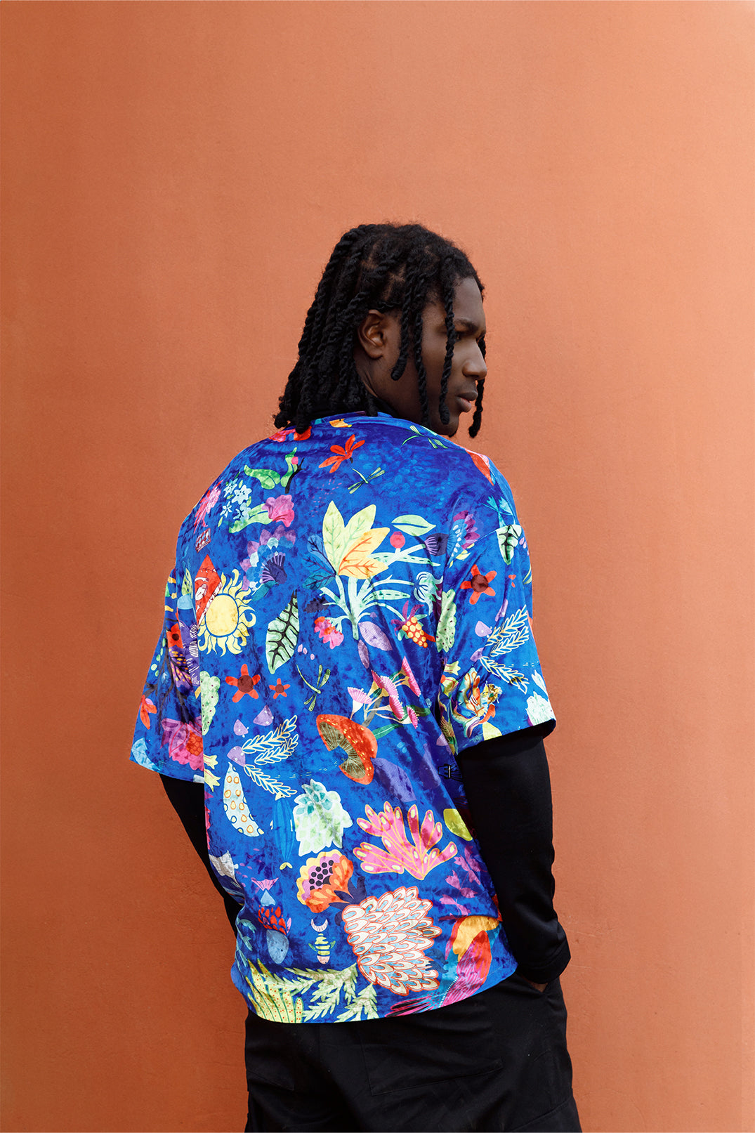 Back view of the blue velvet unisex oversized T-shirt worn by a model, featuring an exclusive artistic graphic and short sleeves.