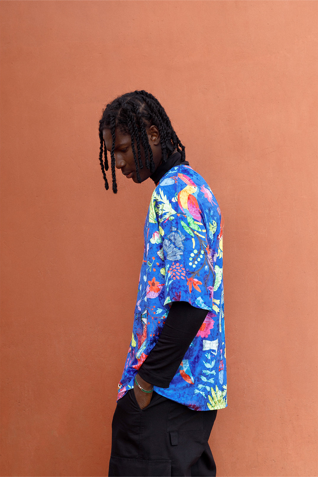 Side view of the blue velvet unisex oversized T-shirt worn by a model, featuring an exclusive artistic graphic and short sleeves.