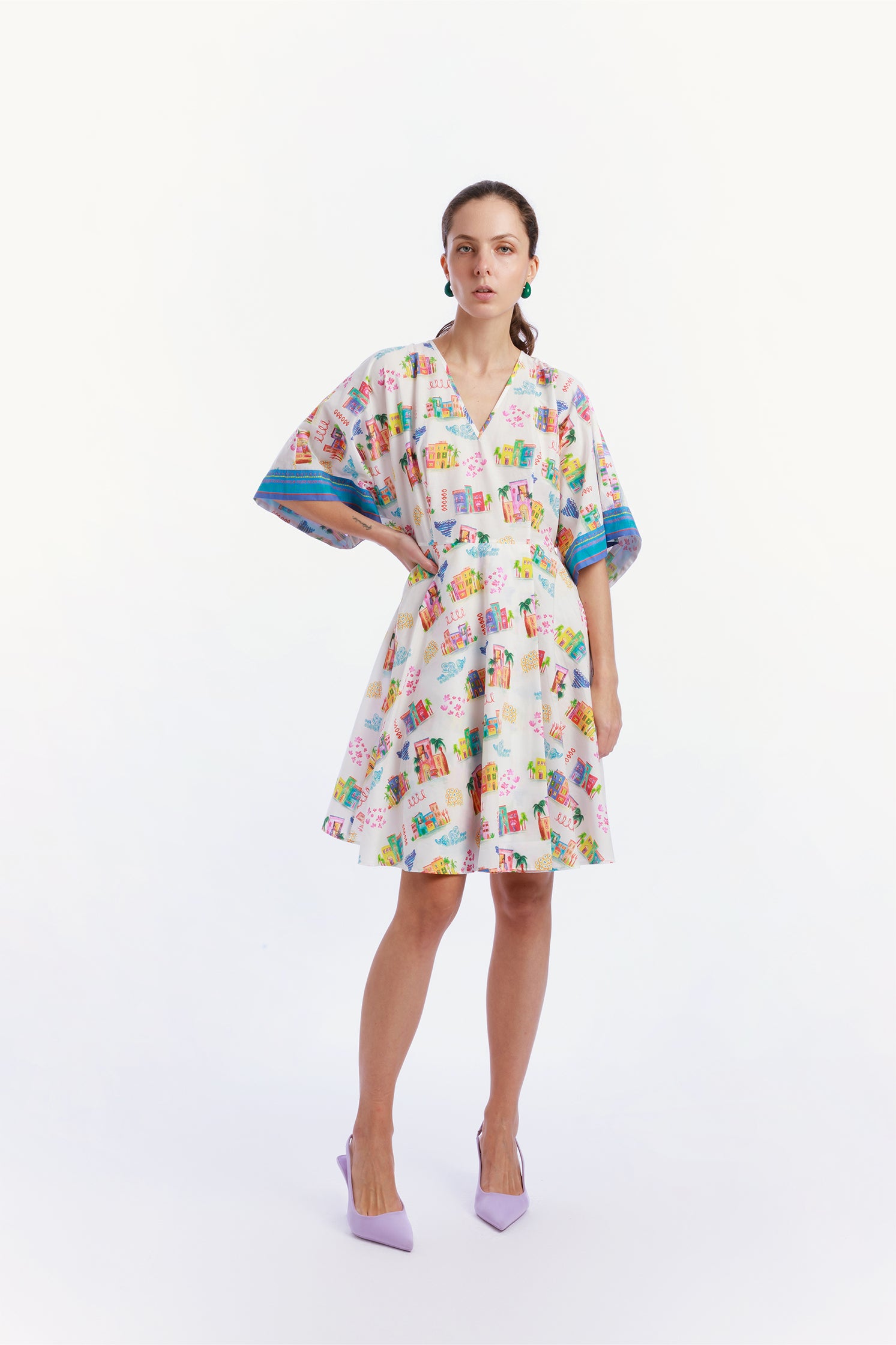 Wrap dress worn by a model, featuring an exclusive Homi Too "Casette" print of colorful Mediterranean houses, flattering wrap cut, kimono sleeves and lightweight flowing fabric.