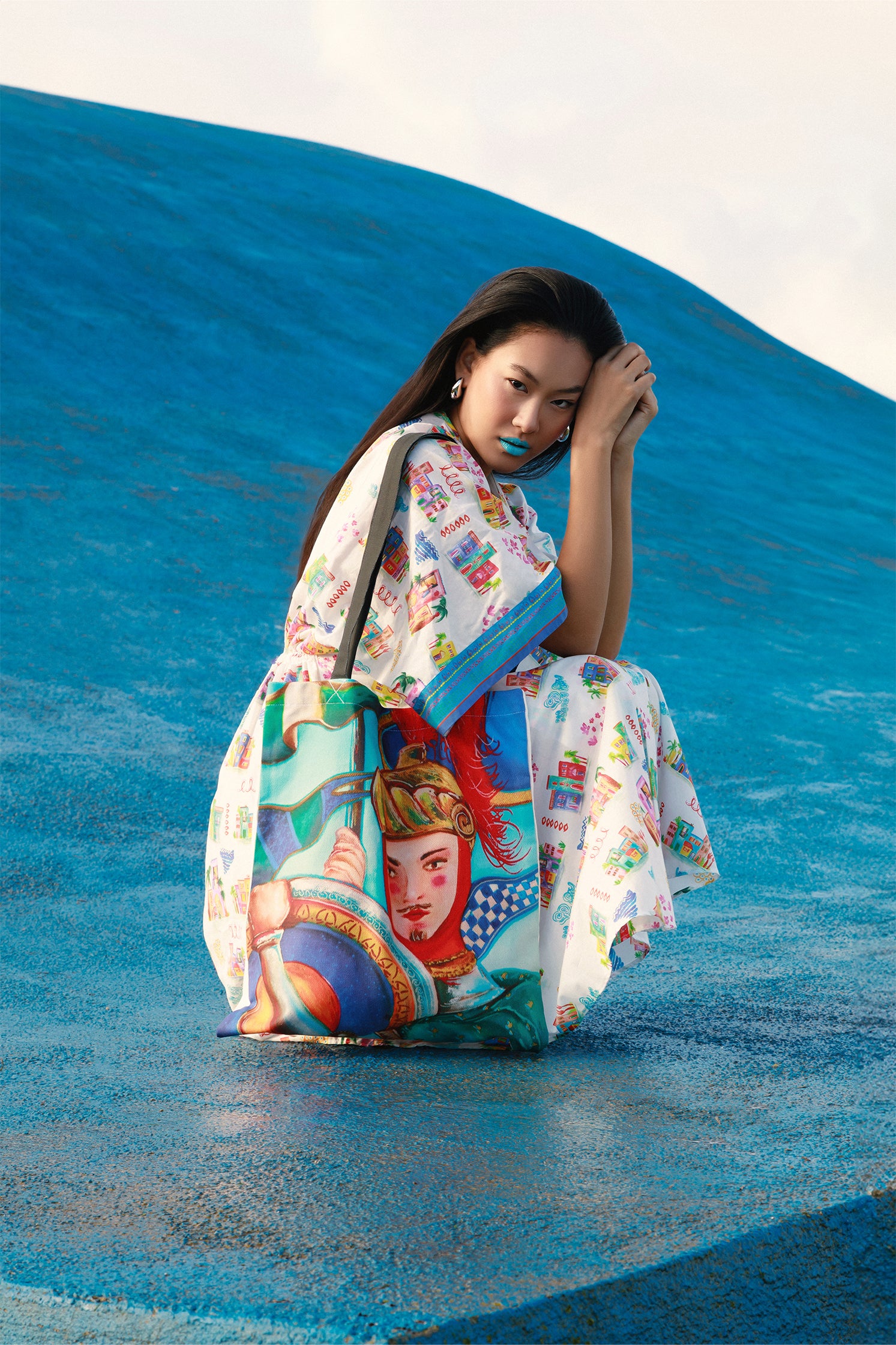 Natural cotton shopper bag featuring an exclusive "Sicilian Puppet" print derived from a hand-painted illustration, showing vibrant colors and refined details worn by a model.