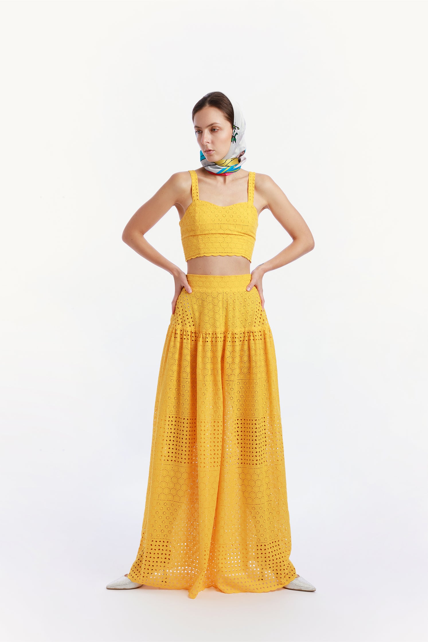 Front view of the pure silk scarf 90x90 cm worn around the head by a model, featuring a vibrant illustration of a Vespa in a colorful Sicilian landscape.