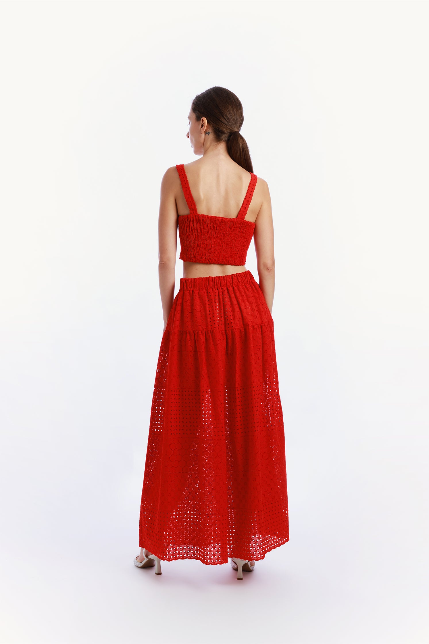 Back view of the red sangallo set worn by a model, featuring a long skirt with elastic waistband and a top with elasticated back, offering elegant and comfortable fit.