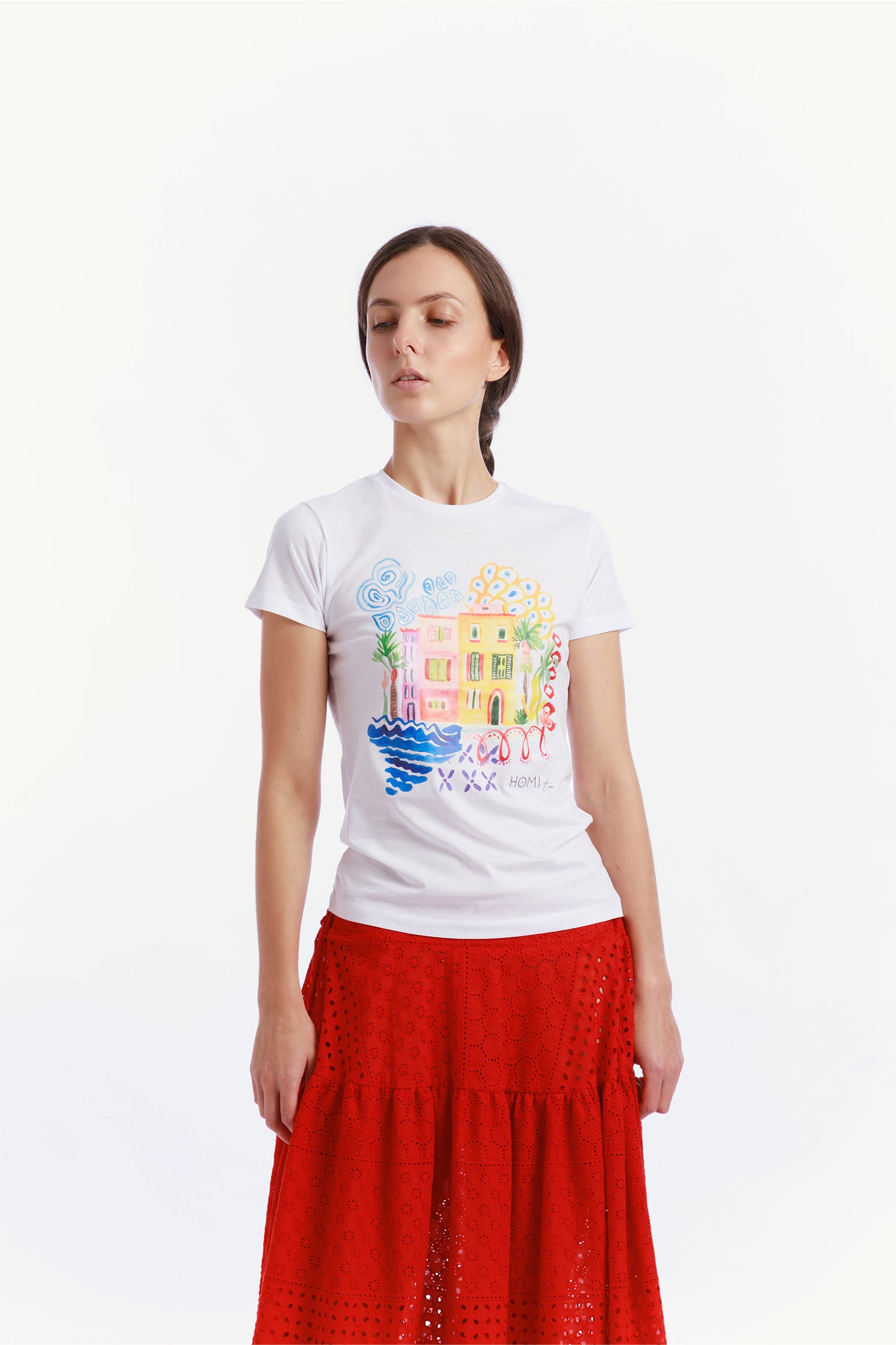 Slim-fit white T-shirt made of high-quality cotton, worn by a model, featuring a modern cut and a graphic on the front depicting small colorful houses.