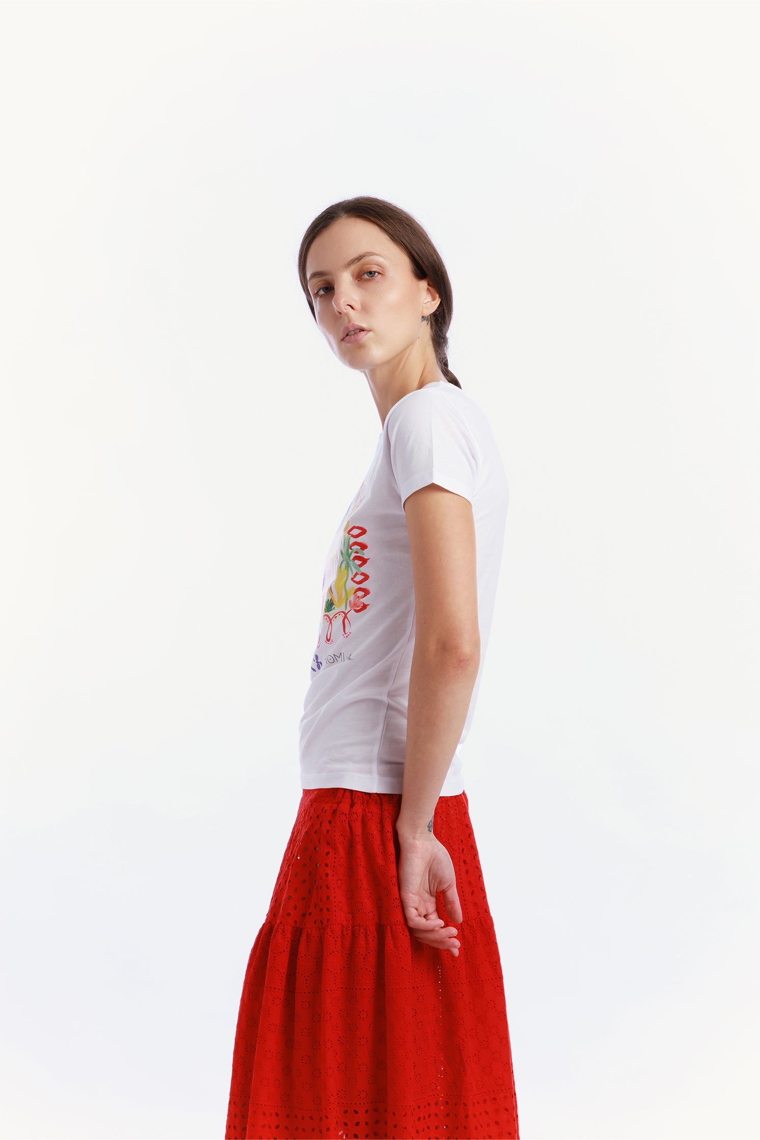 Side view of the slim-fit white T-shirt made of high-quality cotton, worn by a model, featuring a modern cut and a graphic on the front depicting small colorful houses.
