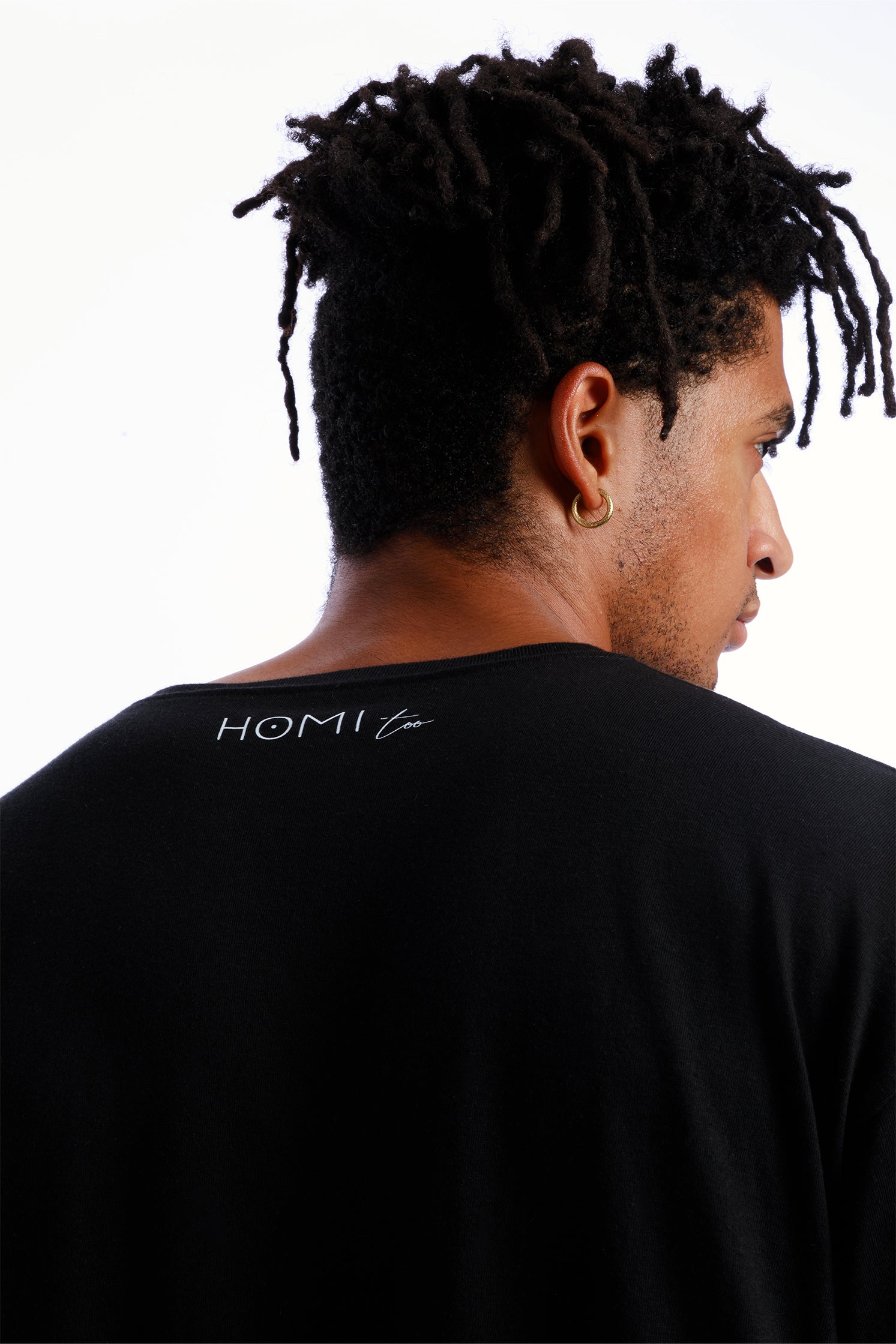 Close-up of the back of the black oversized unisex T-shirt made of 100% high-quality cotton, worn by a model, featuring the "Homi Too" logo printed on the collar.