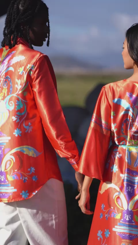 Long-sleeved shirt worn by a model, featuring an exclusive Homi Too pattern on the back with a red-orange background and turquoise embroidery on the heart side