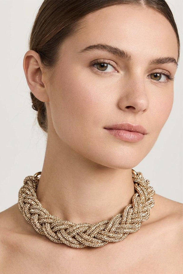 Gold braided necklace with a chunky design and sparkling embellishments worn by a model.