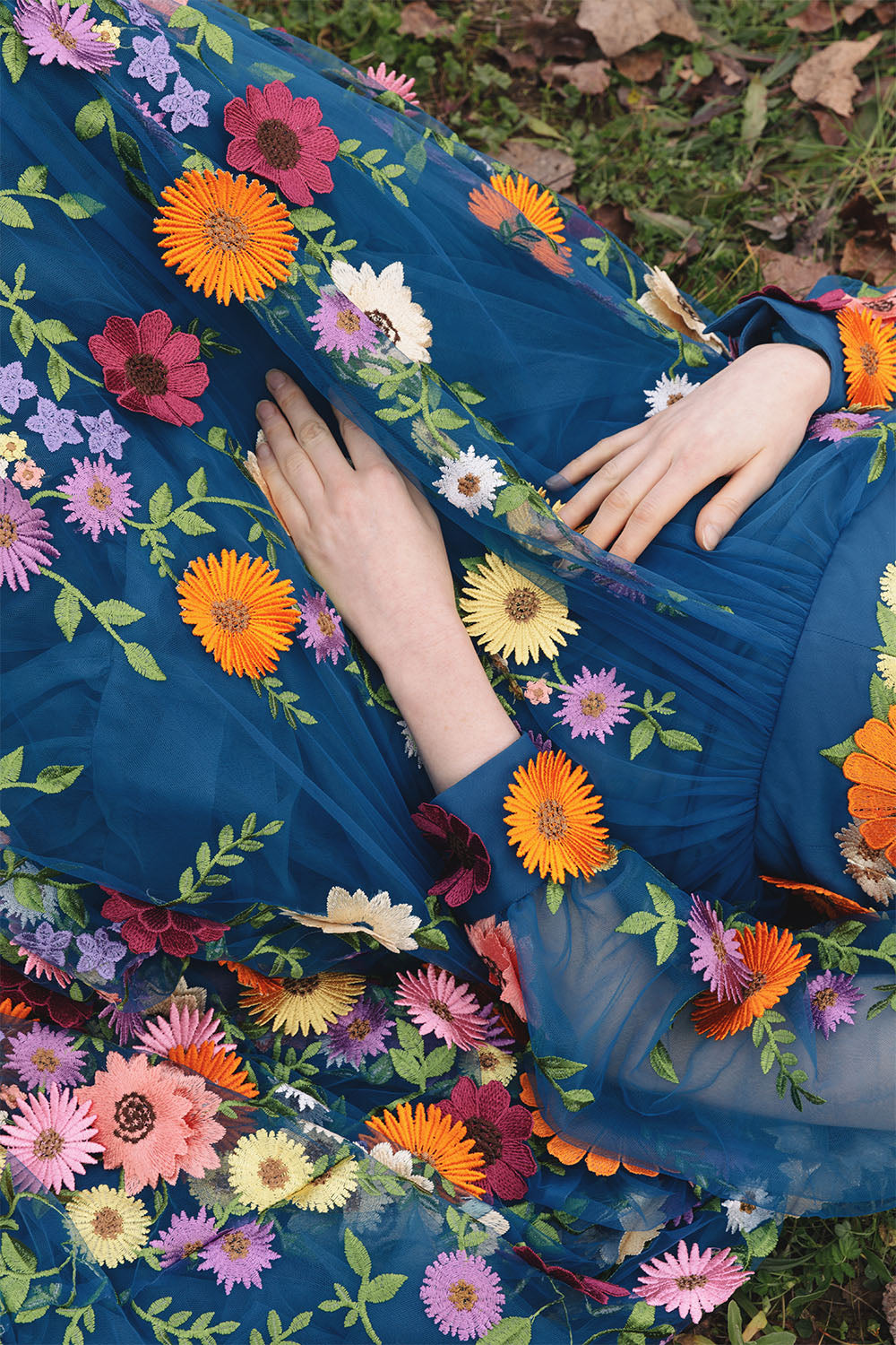 Detail of the blue floral embroidered dress worn by a model.
