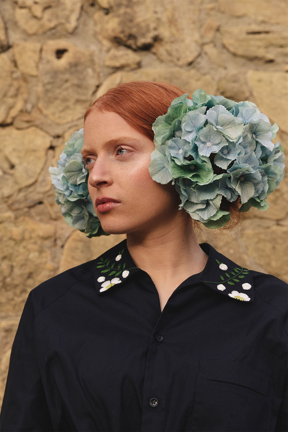 Black shirt with floral embroidered collar worn by a model.