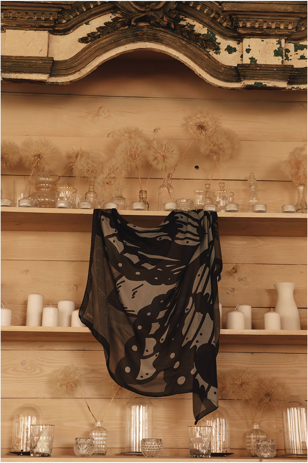 Square modal and cashmere scarf in black, gray and taupe tones, featuring a large stylized moth with anatomical wing details and a dark border.