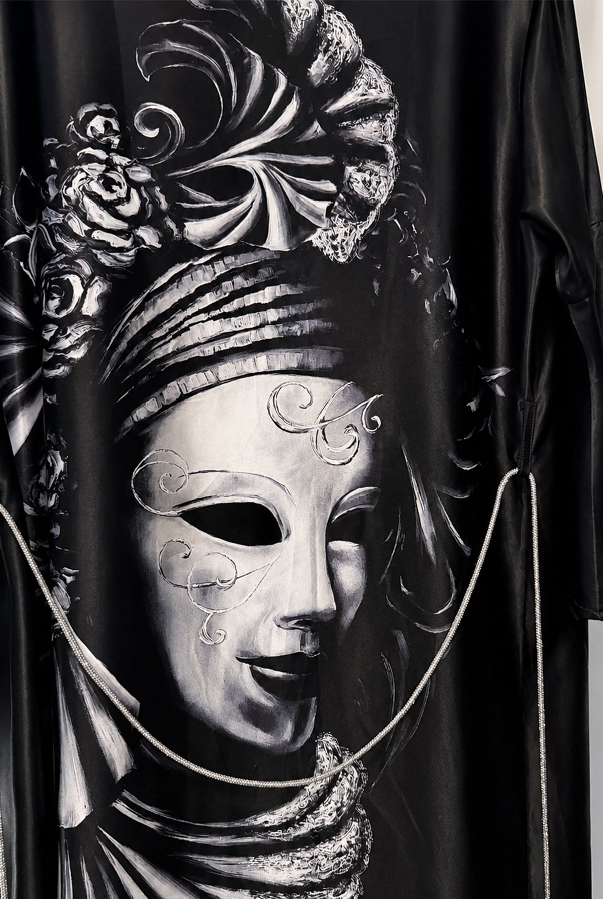 Close-up of the black fabric and the detailed black-and-white Venetian mask and floral graphic.
