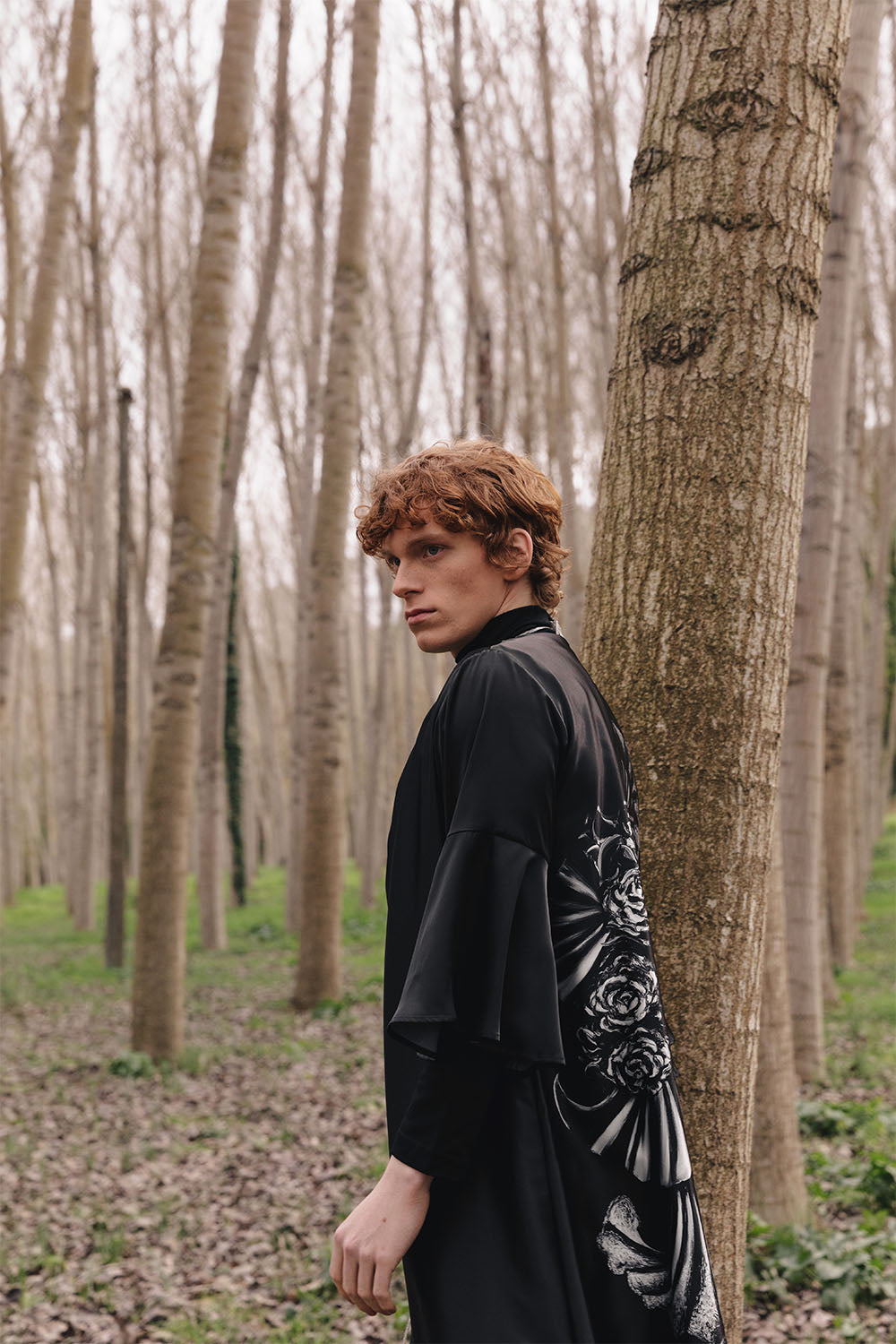 Black kimono worn by a model, featuring wide sleeves and a large black-and-white Venetian mask graphic on the back.