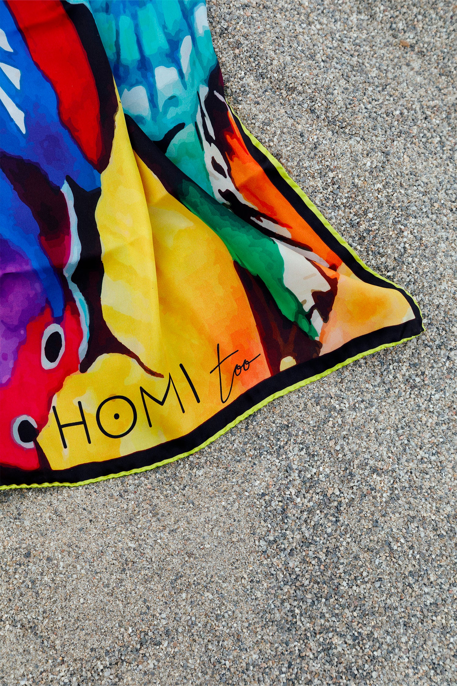 Close-up of the pure silk scarf with butterfly print, showing vibrant details and the "Homi Too" logo inscription on the fabric.
