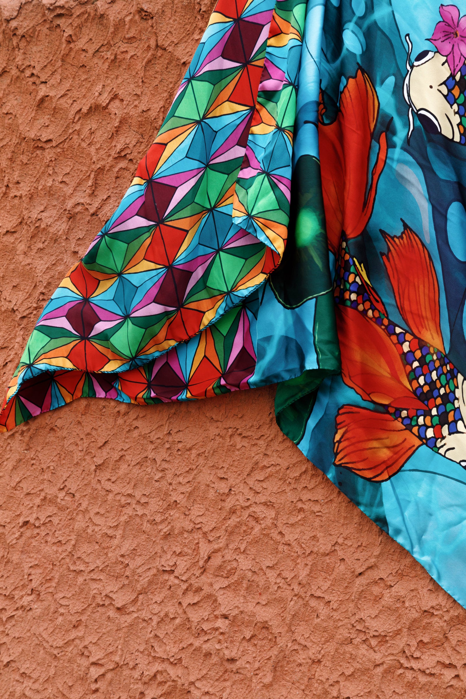 Close-up of the koi carp pattern on the 100% silk scarf, highlighting the fluid lines, vibrant colors and intricate artistic details.