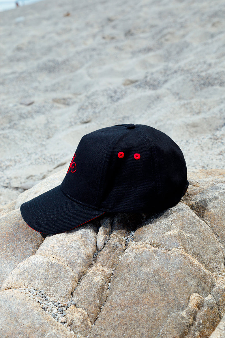Side view of the black peaked cap with red embroidered details, versatile accessory for men and women.