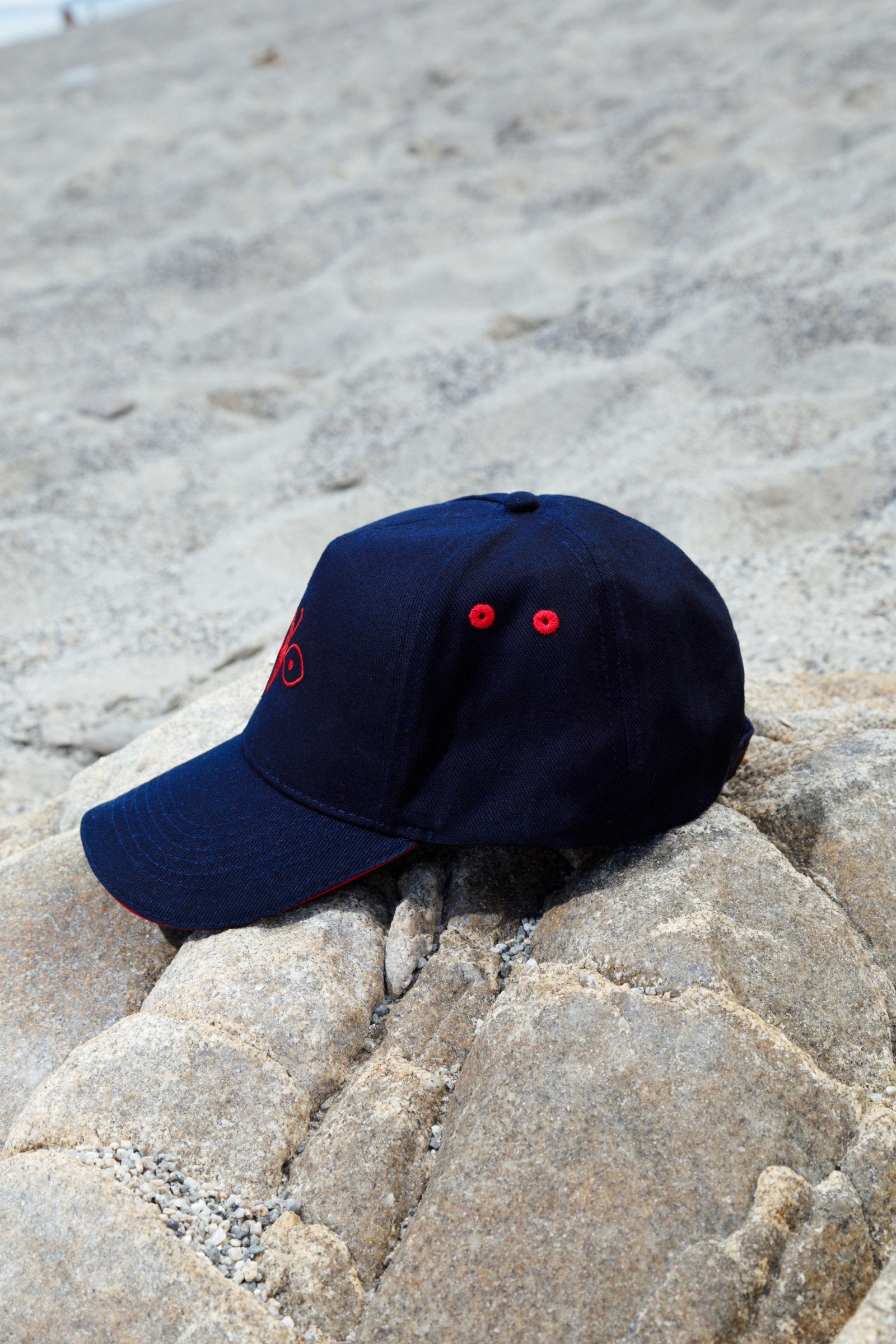 Side view of the blue peaked cap with red embroidered details, versatile accessory for men and women.