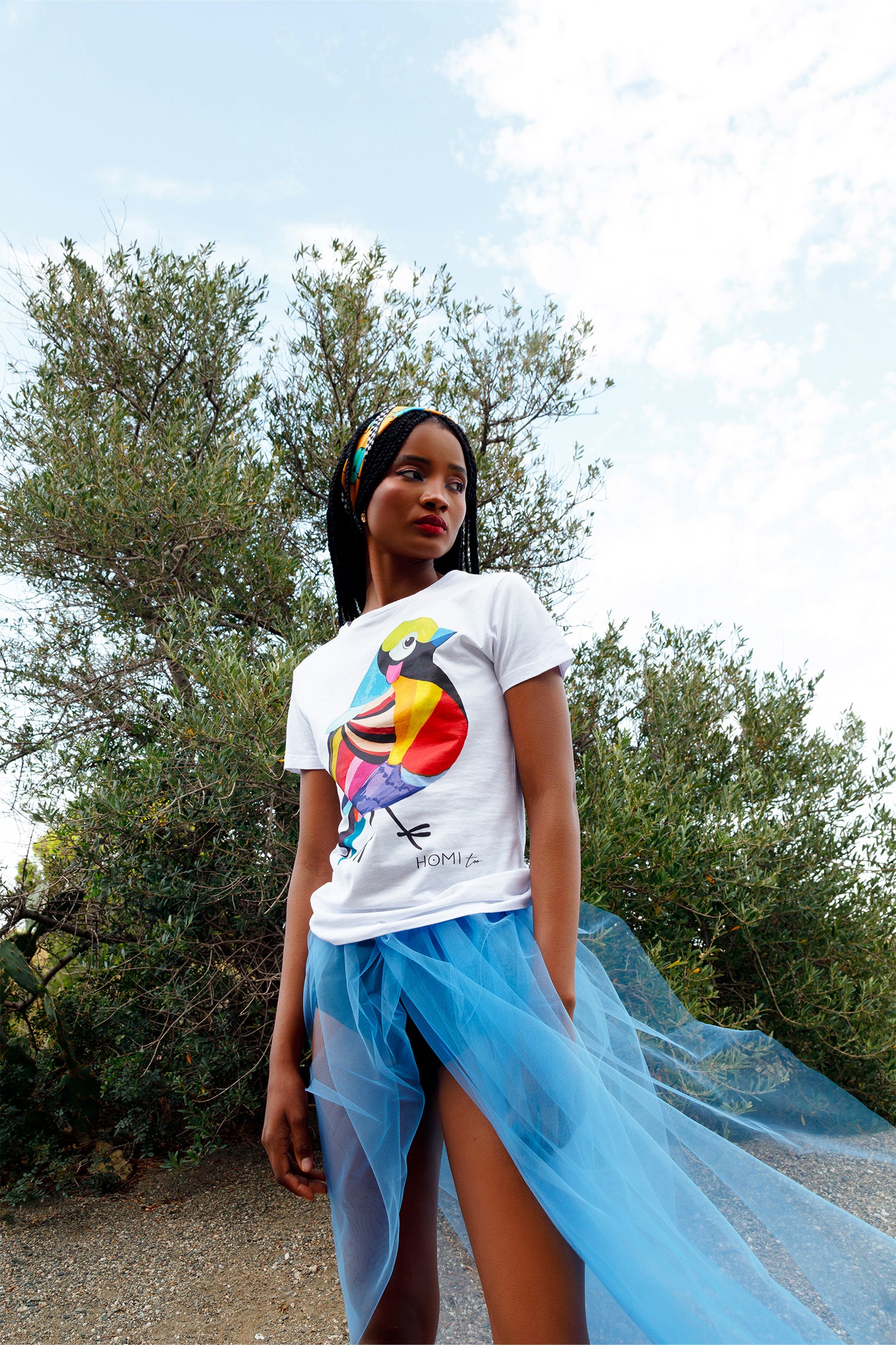 Silk scarf worn on the head by a model, showing the orange graphic with blue and black scarabs and black and white checkered border.