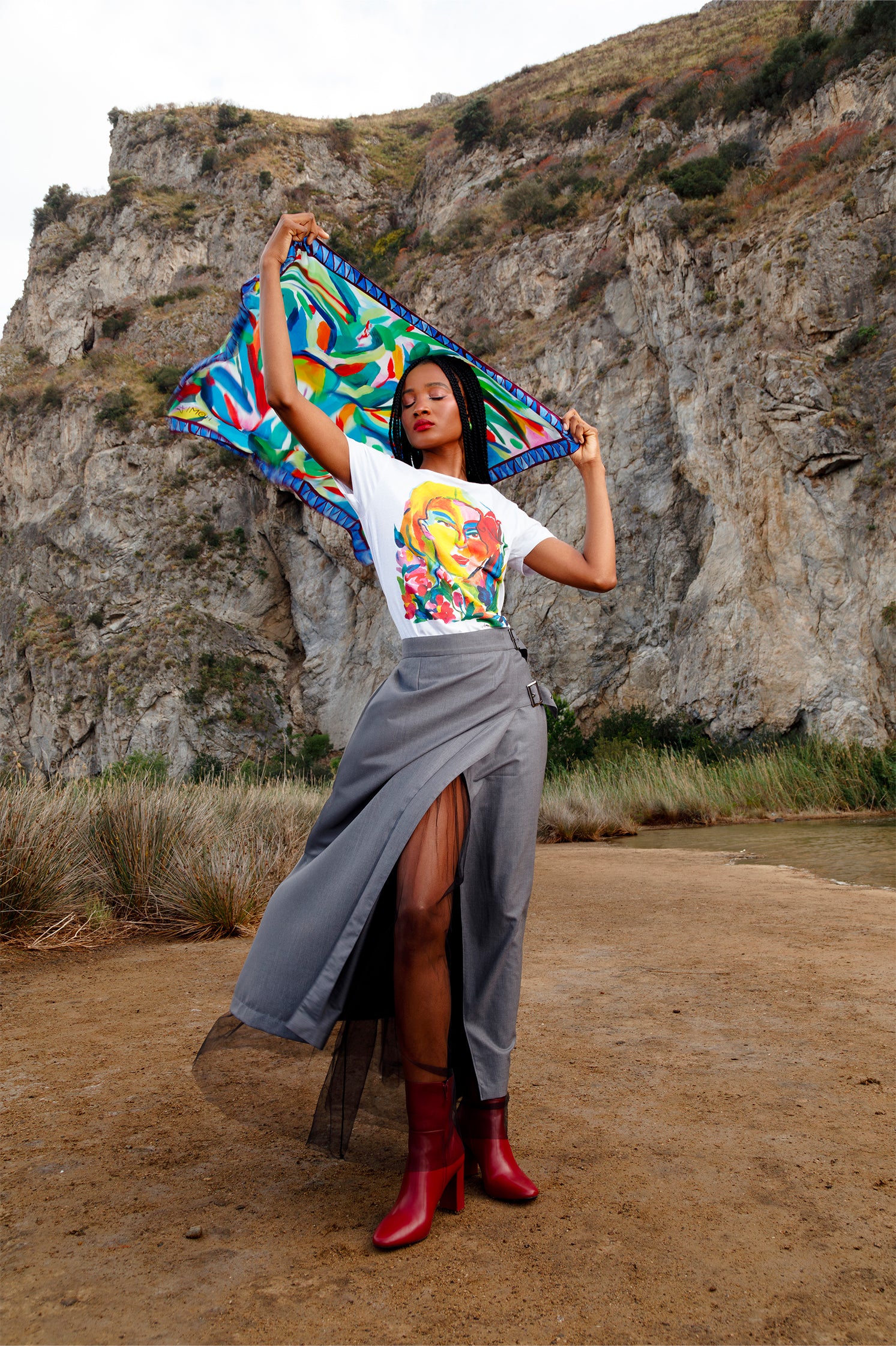 Silk scarf held and waved by a model, highlighting the colorful abstract leaf print and the flowing, lightweight fabric.
