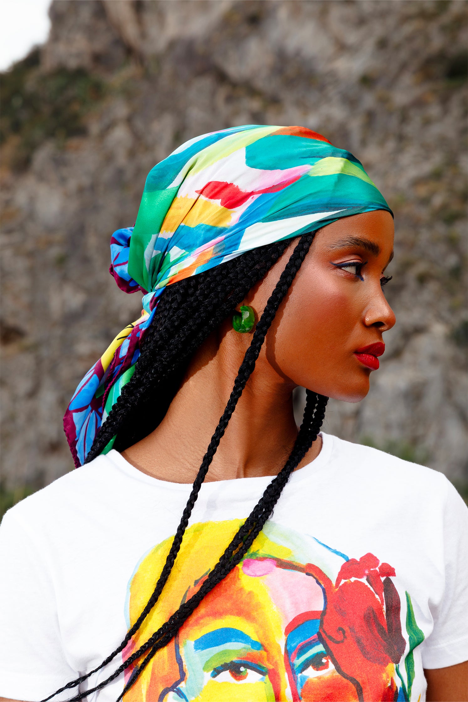 Silk scarf worn on the head by a model, showing the stylized colorful leaf print and contemporary artistic design.