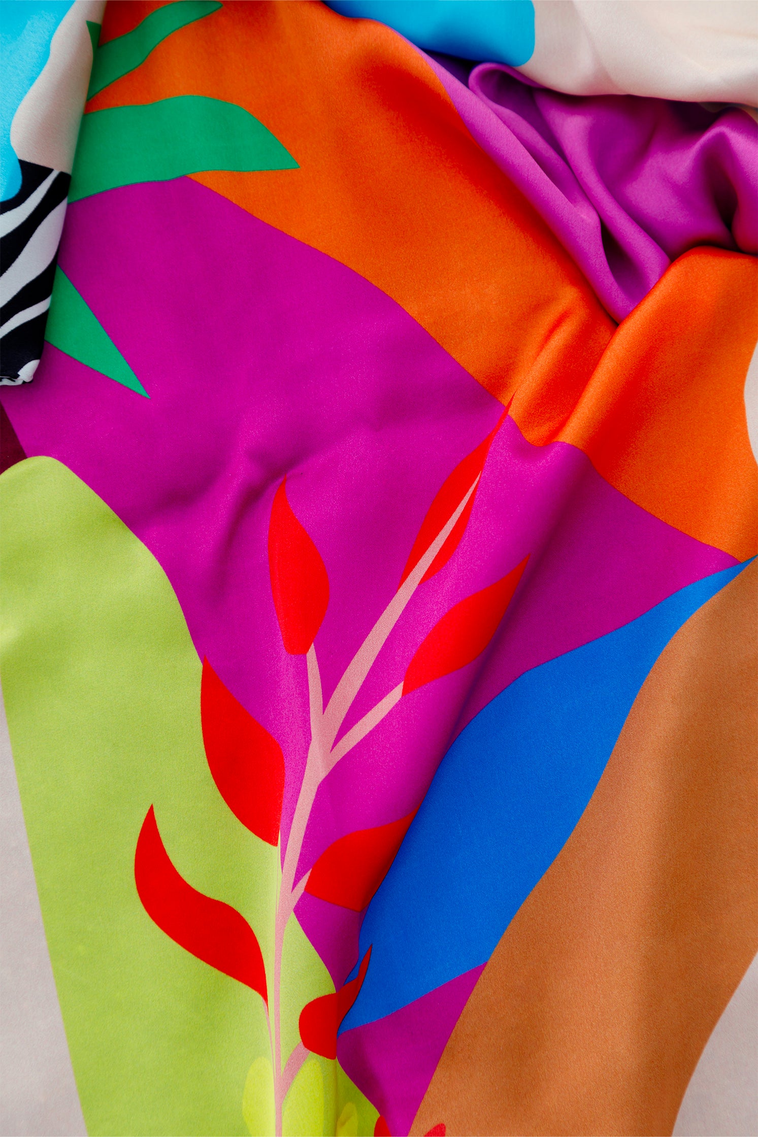 Close-up of the stylized mountain landscape print on the pure silk scarf, highlighting rich colors.