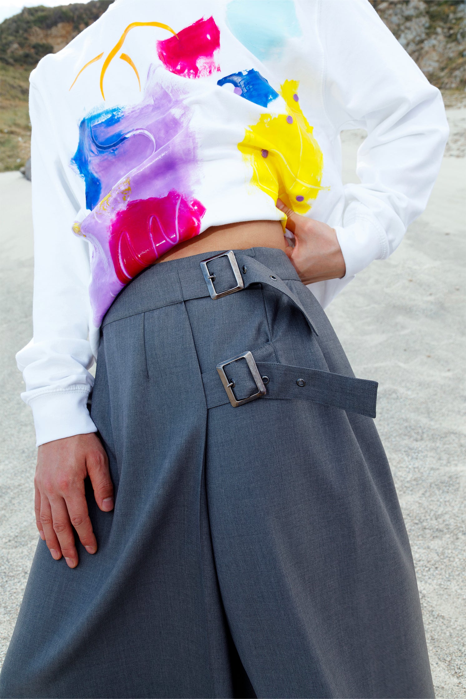 Close-up of the sturdy metal buckle closure on the long gray wrap skirt, highlighting industrial-style detail and adjustable fit.