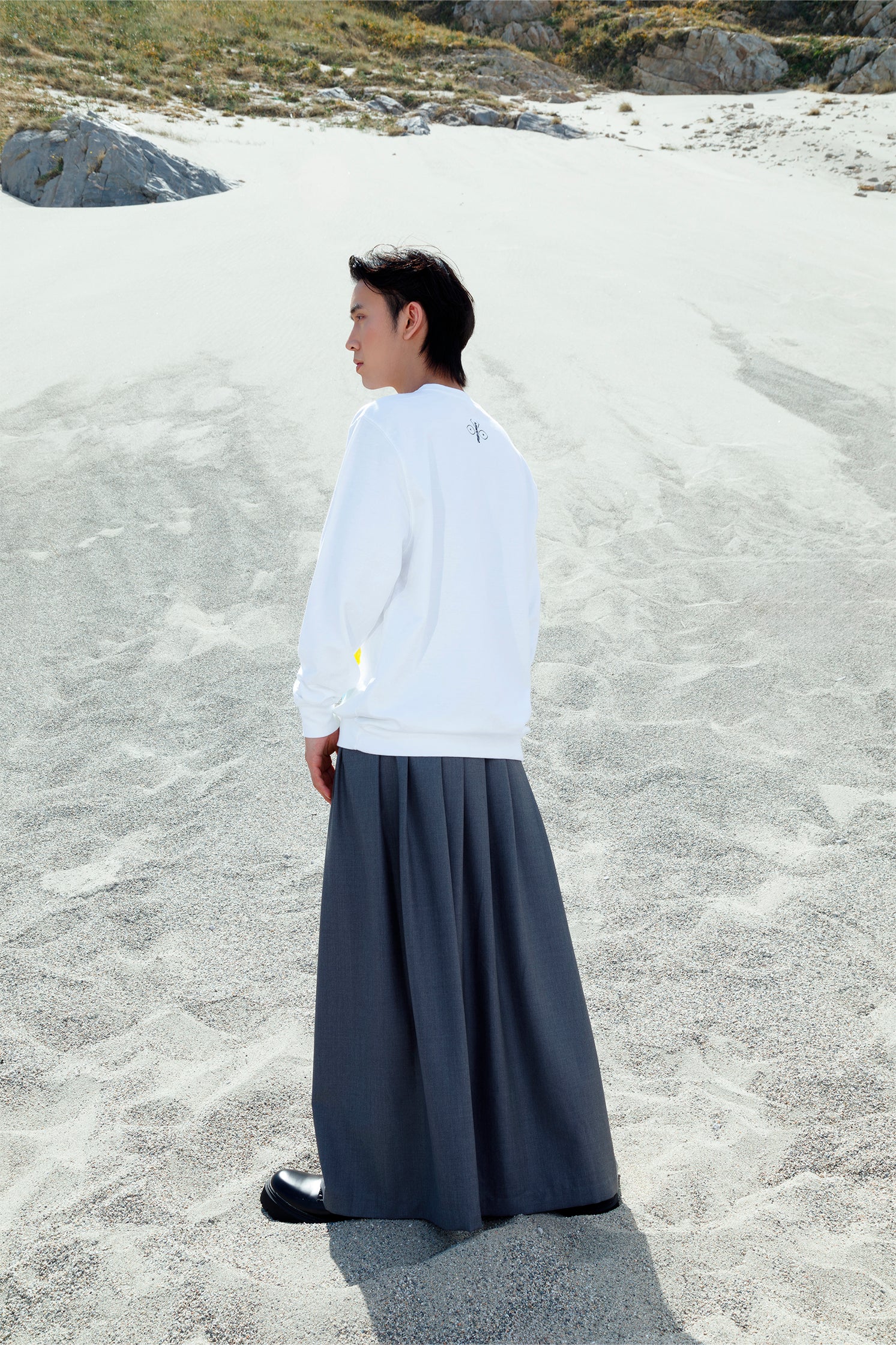 Close-up of the well-defined back folds of the long gray wrap skirt, showing volume, movement, and sophisticated drape.