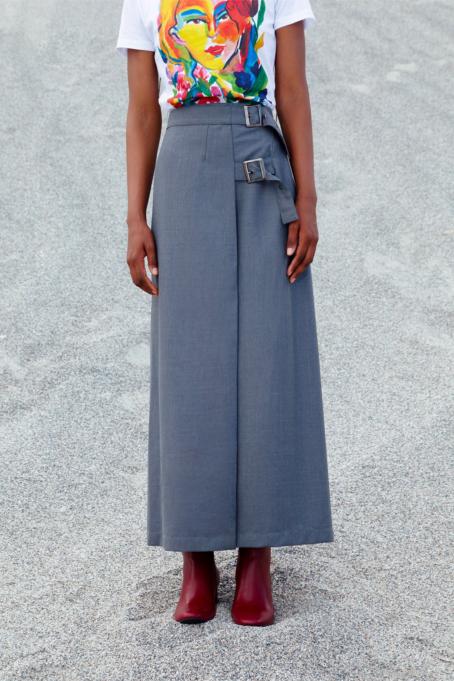 Long gray wrap skirt in cool 100% wool worn by a model, featuring elegant wrap design, lightweight breathable fabric and adjustable metal buckle closure.