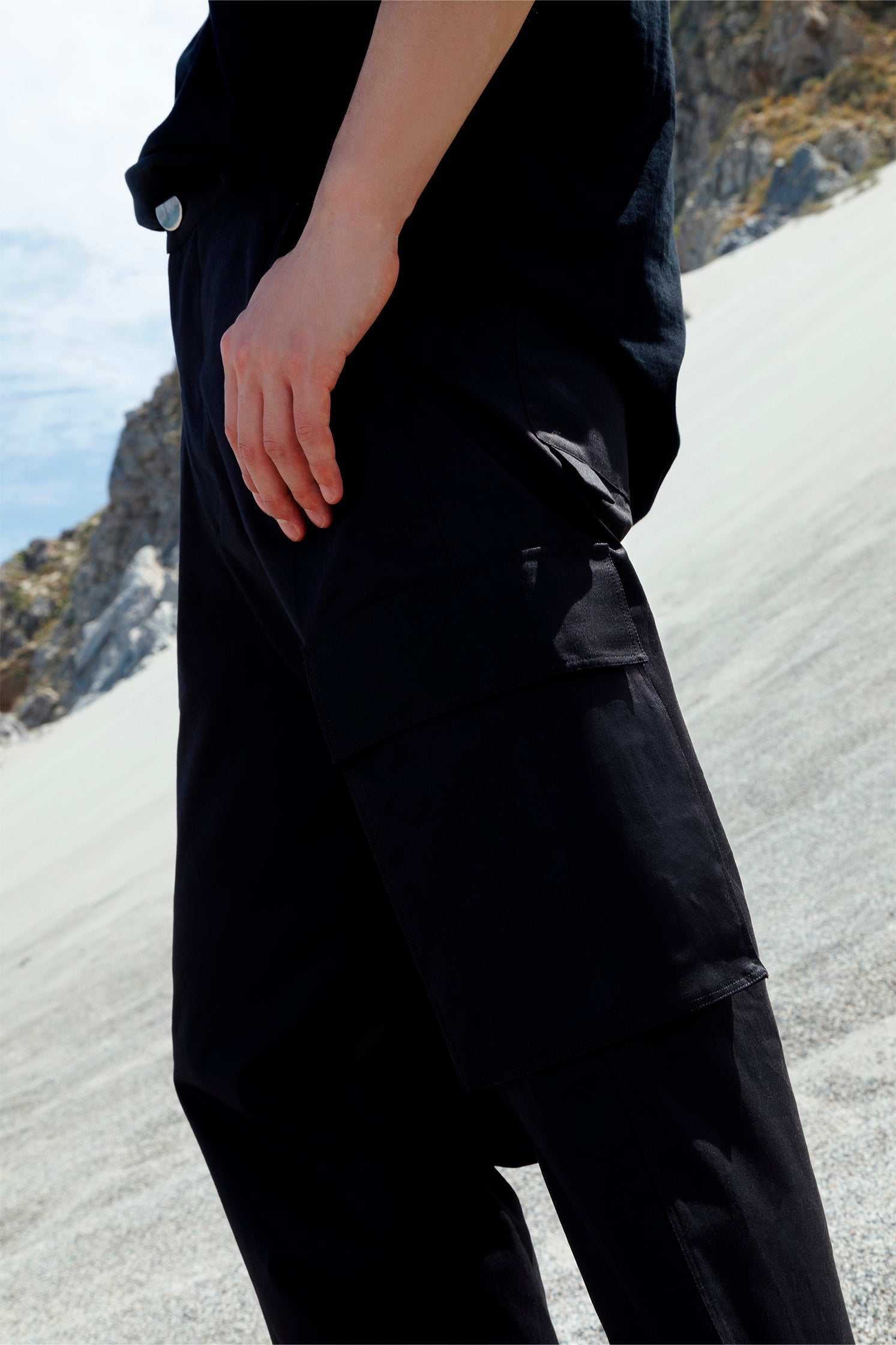 Close-up of the side patch pockets on the black cotton cargo pants, highlighting practical design and spacious storage.