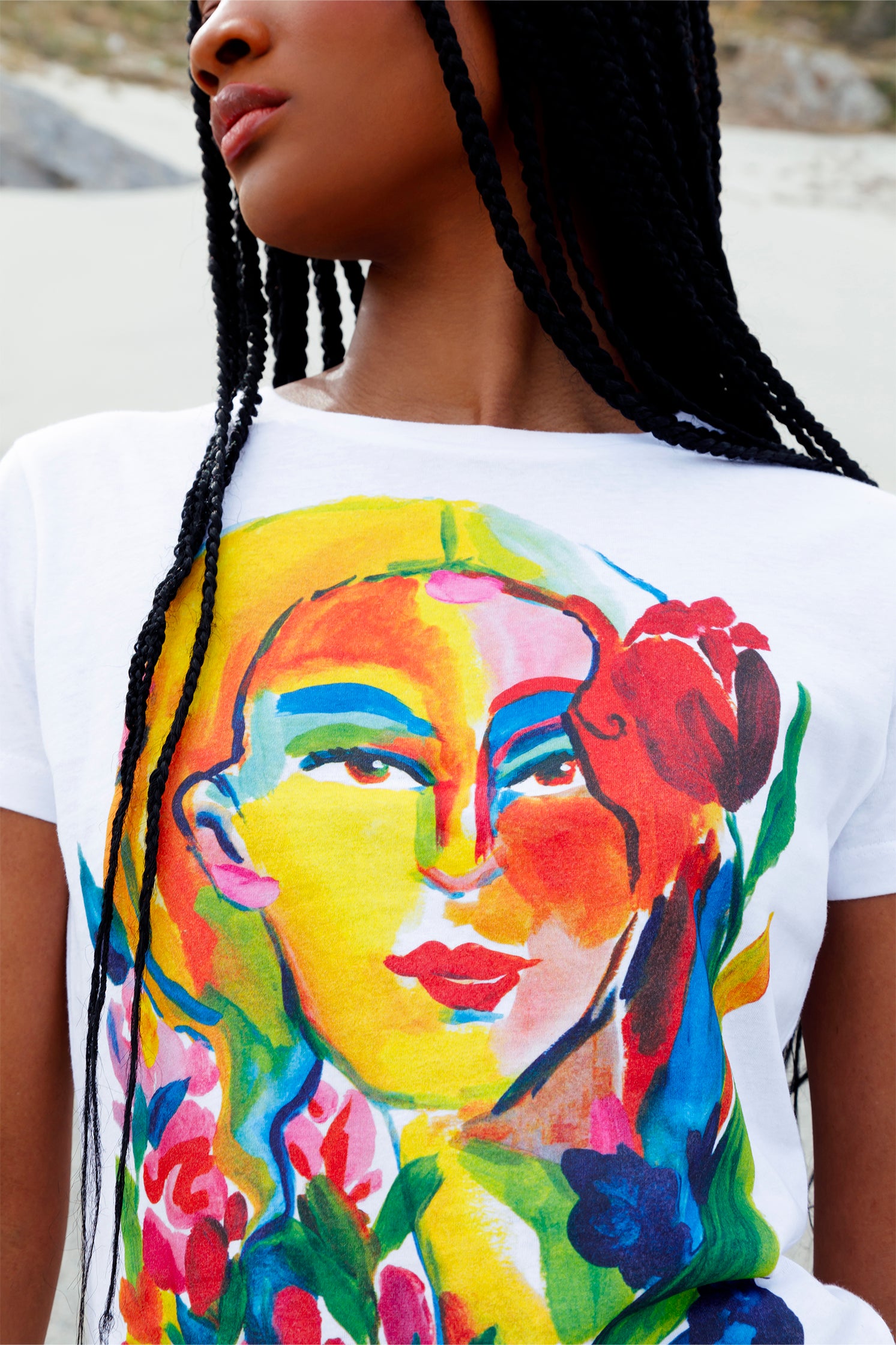 Close-up of the colorful female face print on the slim women's white t-shirt, showing artistic brushstrokes and vibrant details.