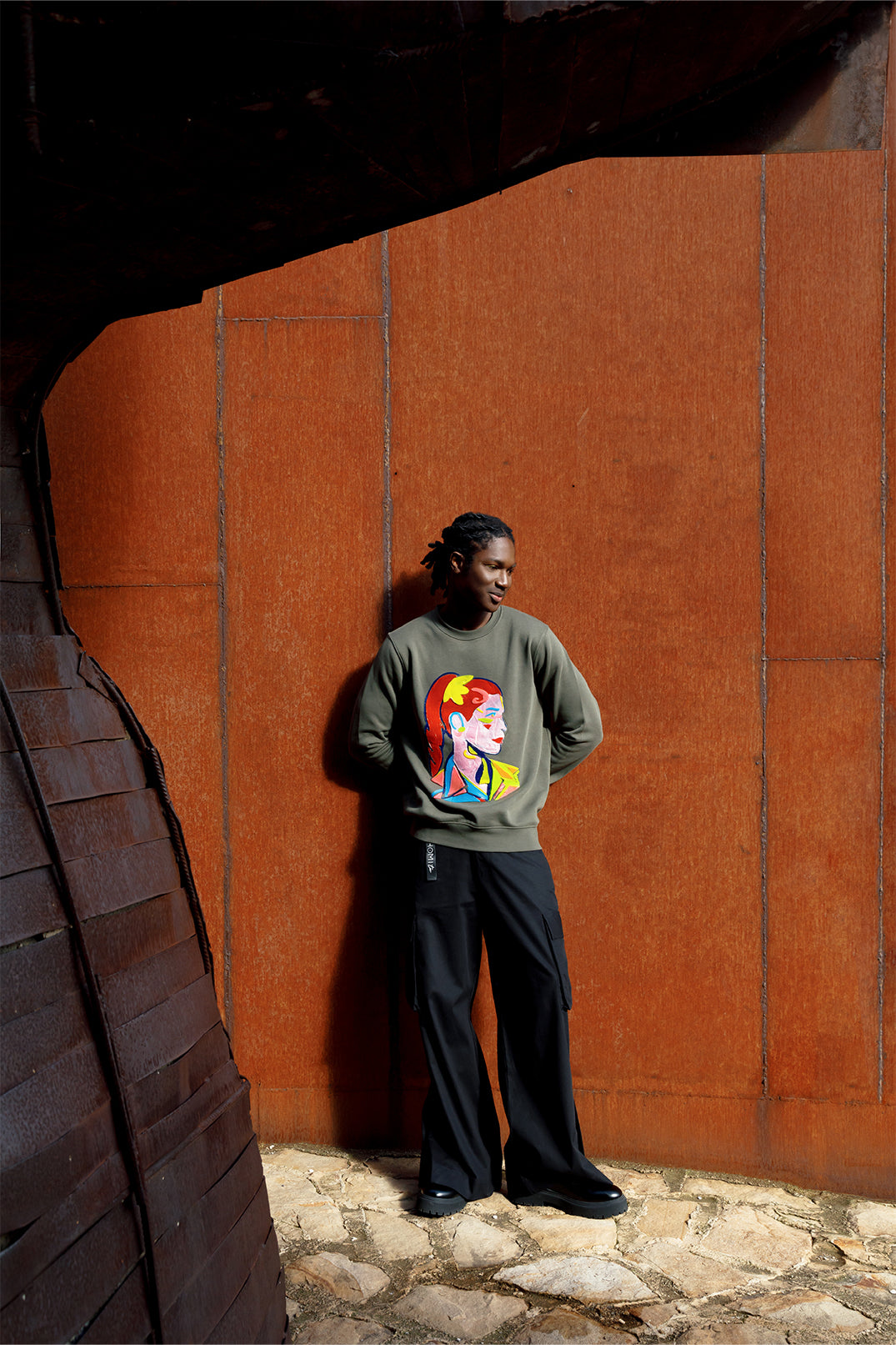 Unisex oversized green sweatshirt worn by a model, featuring a hand-crafted raised silicone abstract geometric face print, creating a three-dimensional and tactile effect.