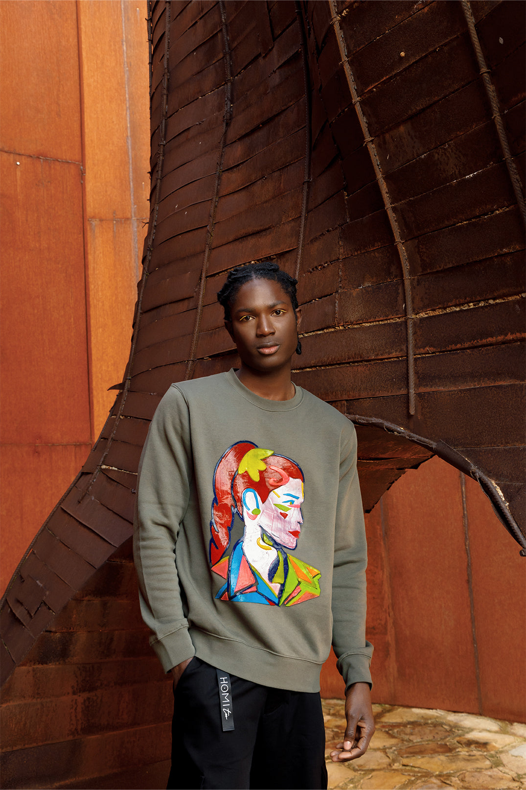 Unisex oversized green sweatshirt worn by a model, featuring a hand-crafted raised silicone abstract geometric face print, creating a three-dimensional and tactile effect.