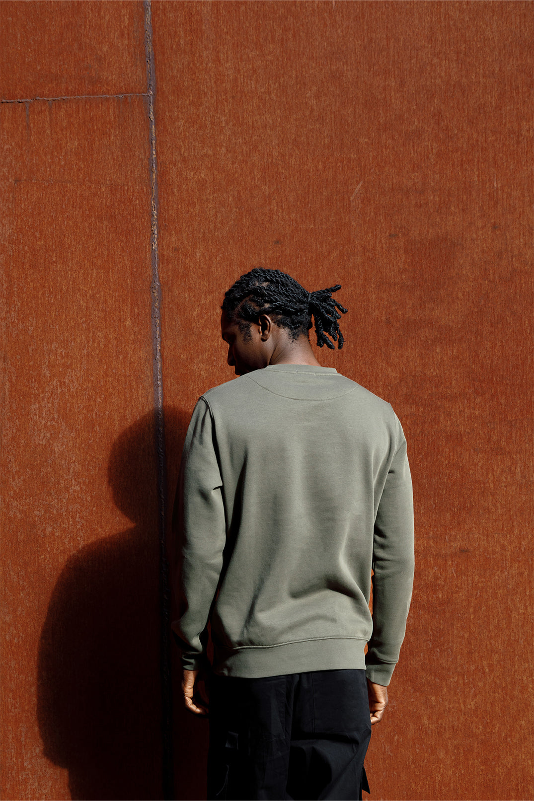 Back of the oversized unisex green sweatshirt worn by a model, showing smooth fabric and stitching.