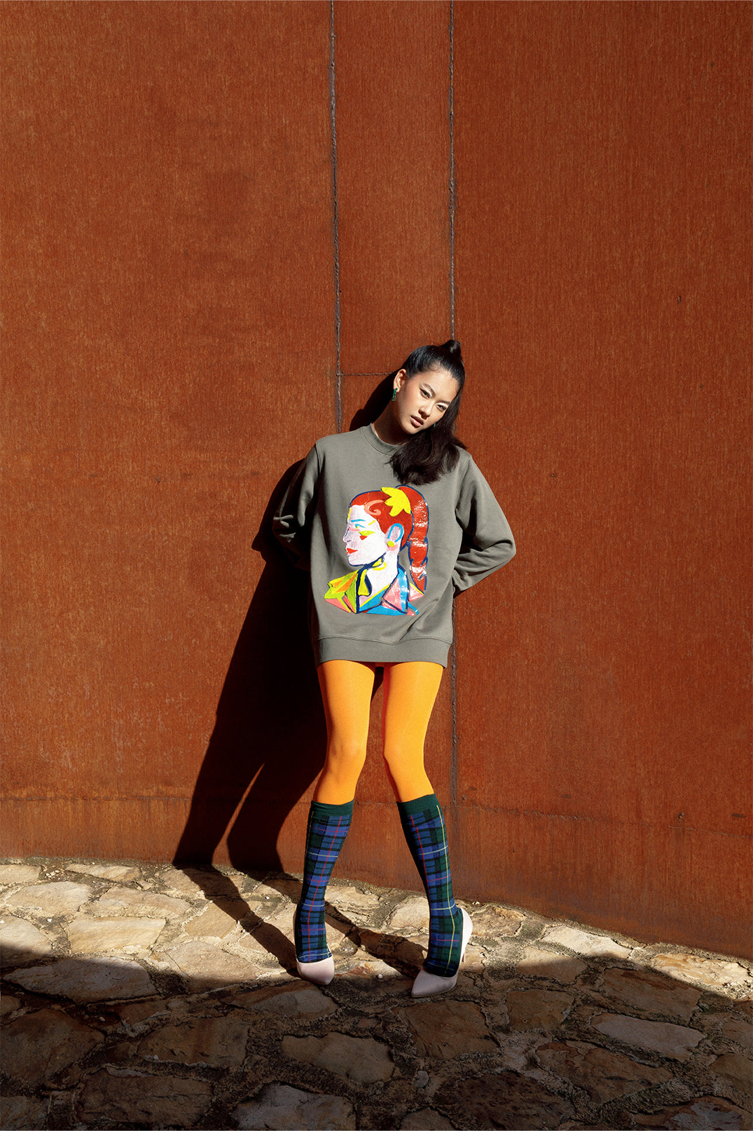 Unisex oversized green sweatshirt worn by a model, featuring a hand-crafted raised silicone abstract geometric face print, creating a three-dimensional and tactile effect.